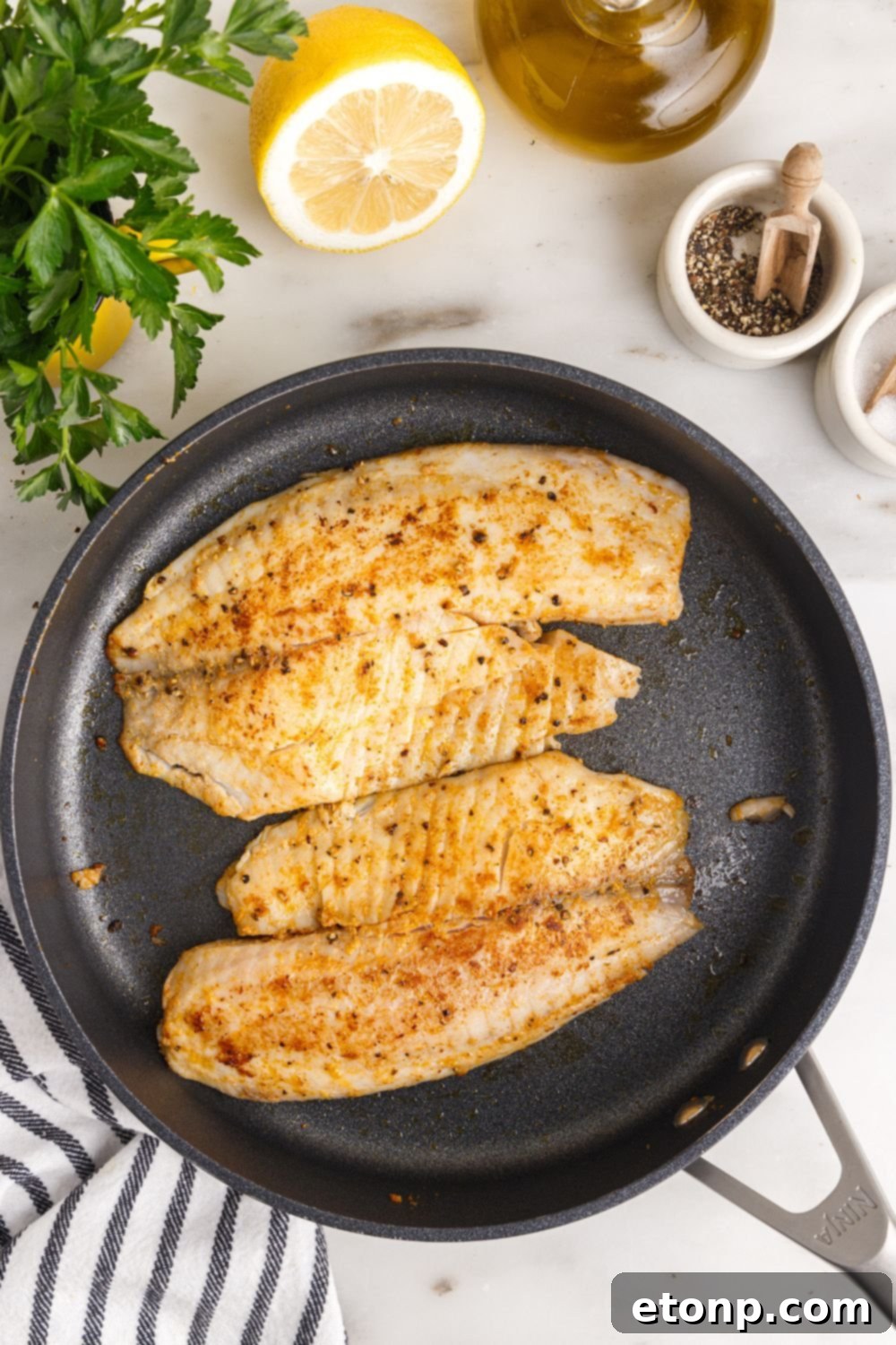 cooked Pan Fried Tilapia in a skillet on table