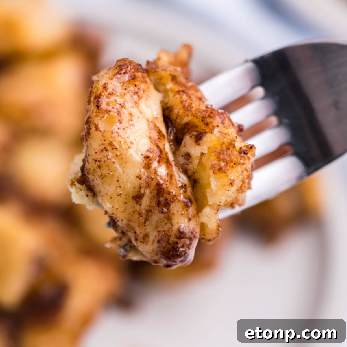 Up close shot of a piece of Cinnamon Roll Casserole on a silver fork, ready to be eaten.