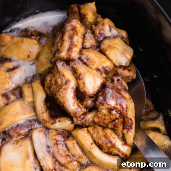Close up view of the Cinnamon Roll Casserole being served using a large silver spoon into a bowl.