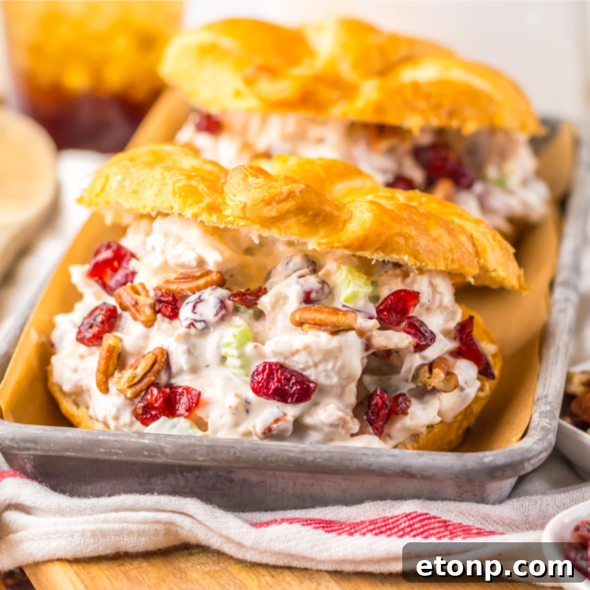 Close up view of a Cranberry Pecan Chicken Salad Croissant on a metal tray sitting on a red and white towel  .