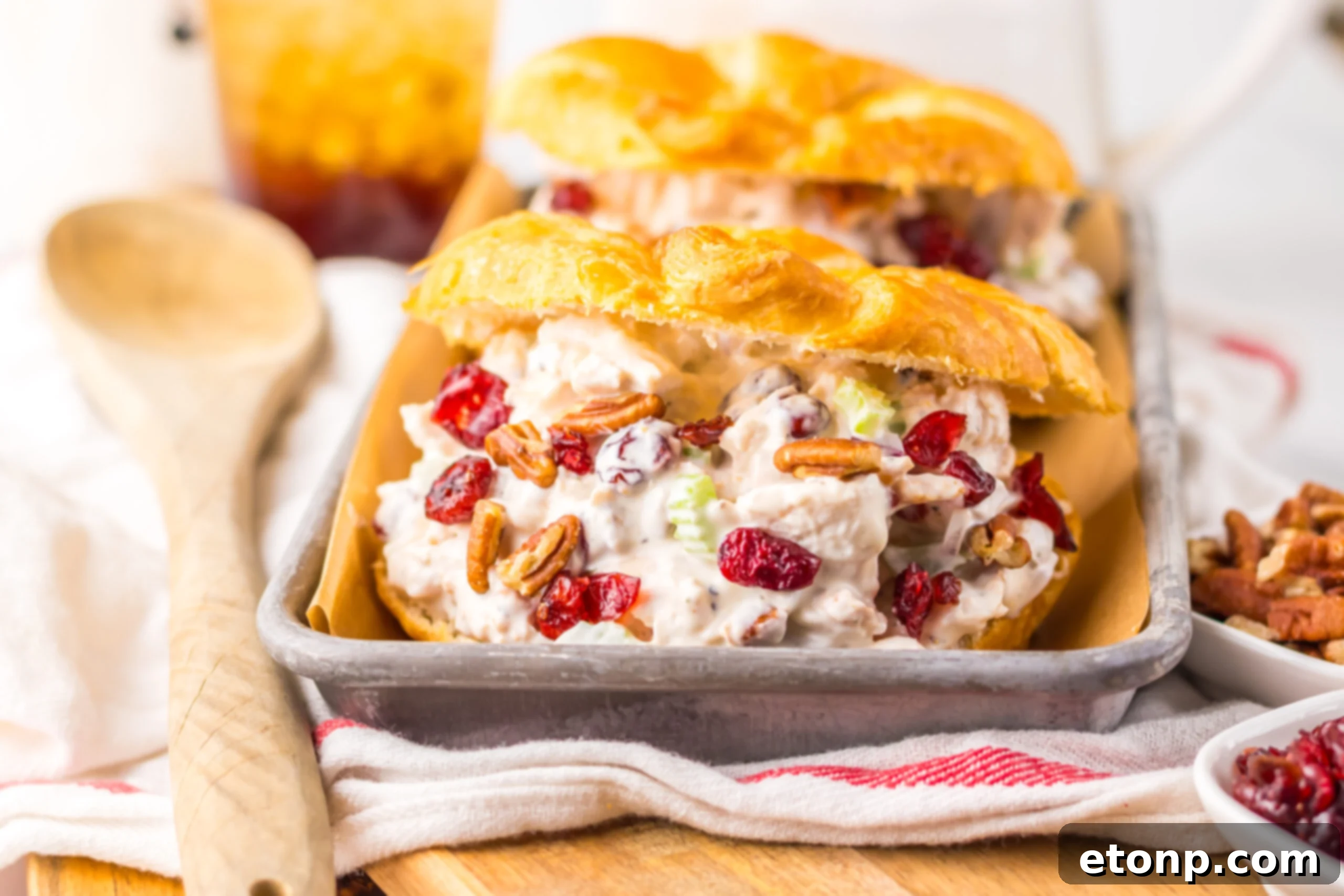 view of a Cranberry Pecan Chicken Salad Croissant on a metal tray sitting on a red and white towel . 