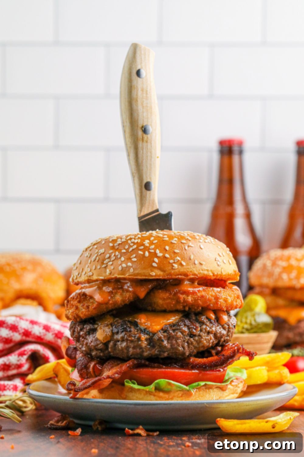 Cowboy Burgers on plates with a knife stabbed in center to show how thick the burgers are 