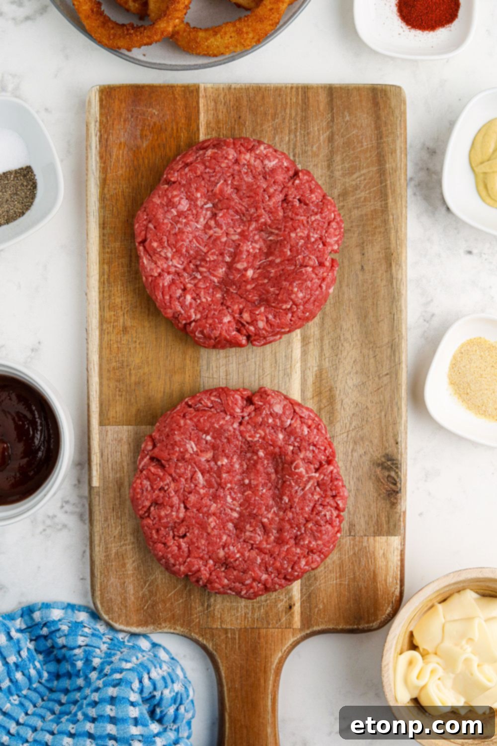 raw hamburger patties on cutting board on table