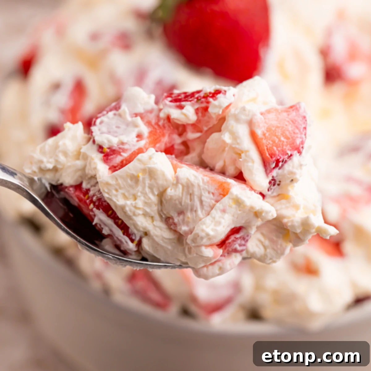 Close up view of the strawberry salad on a silver spoon. 