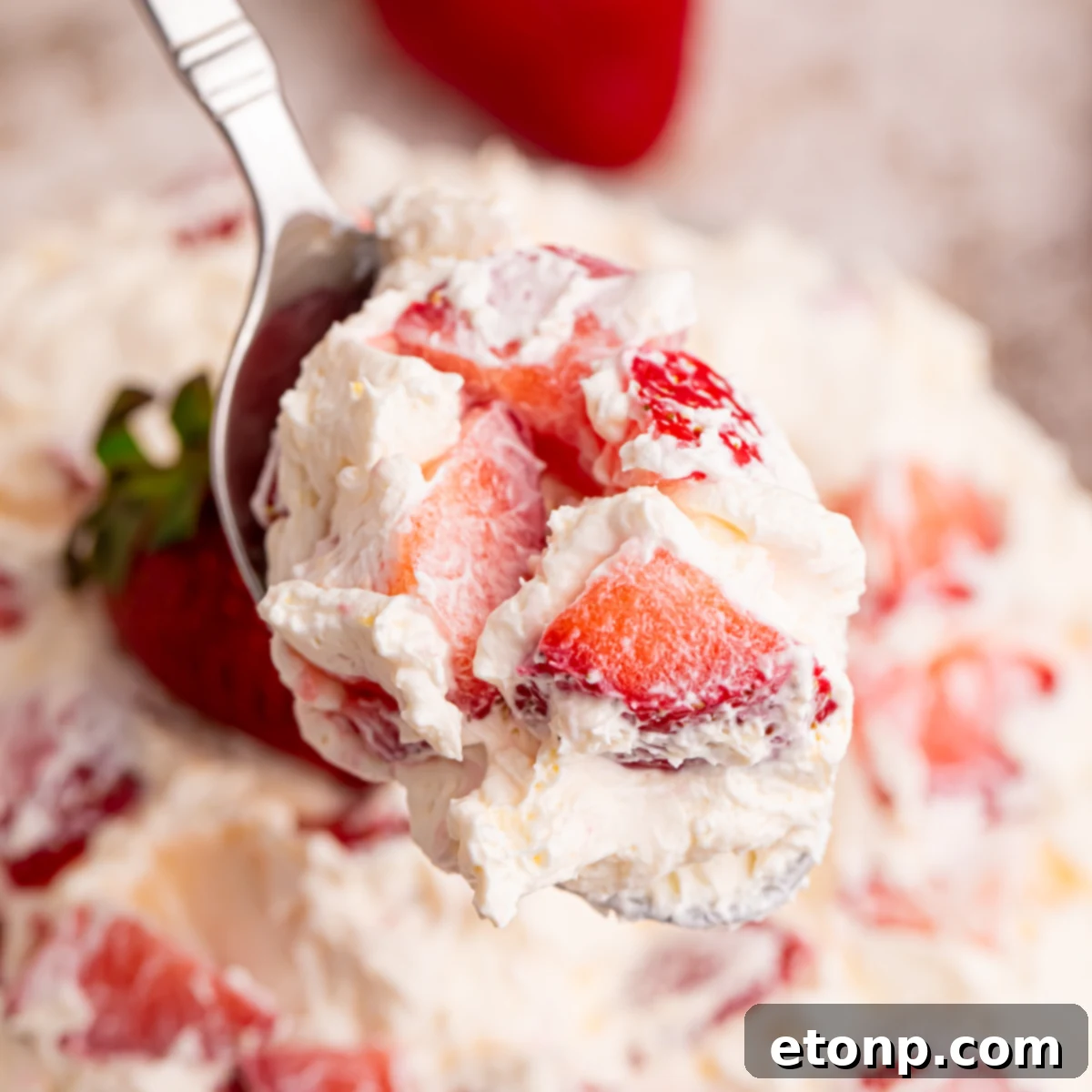 Close up view of the strawberry salad on a silver spoon. 