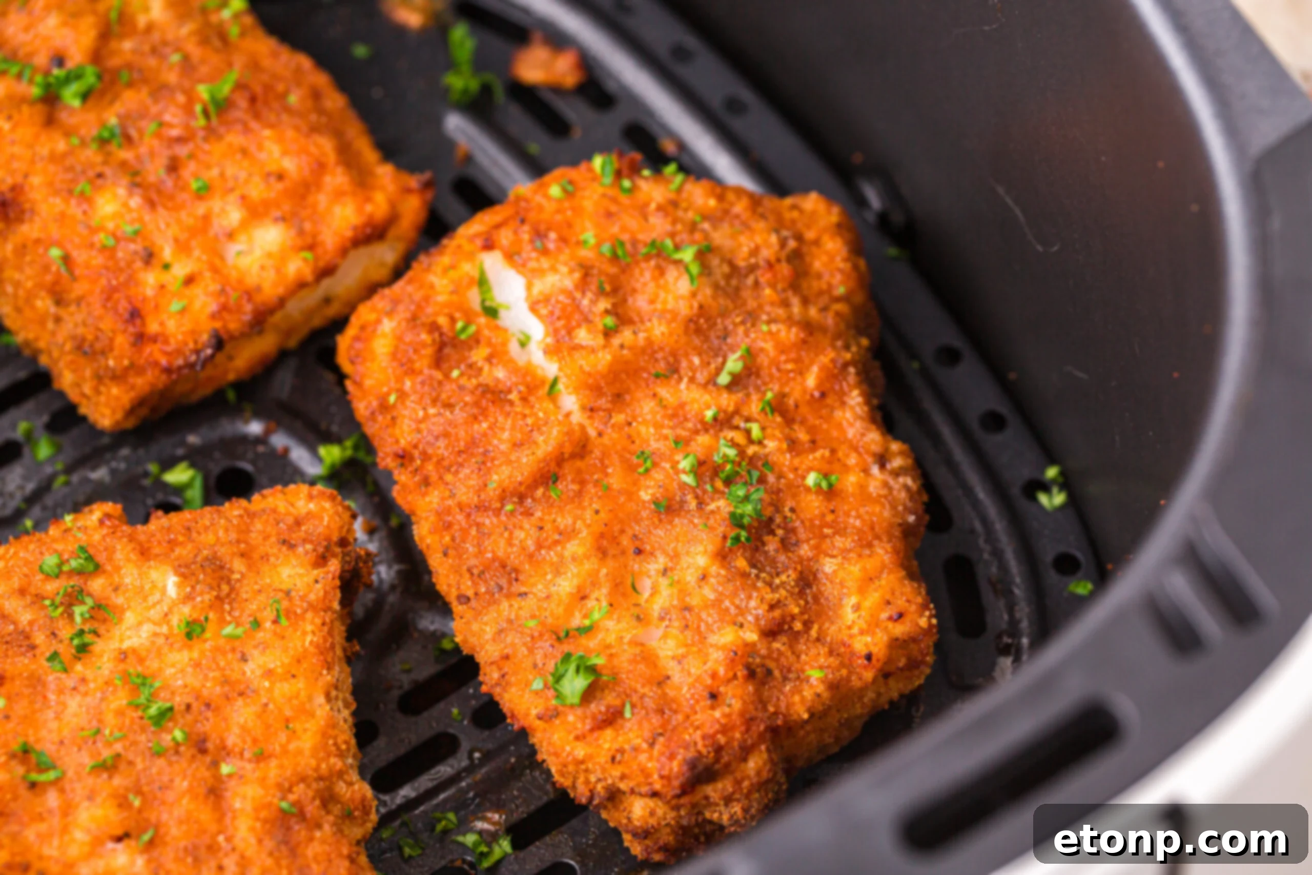 An up-close view of a perfectly golden and crispy air fryer fish fillet inside the air fryer basket, showcasing its appetizing texture.