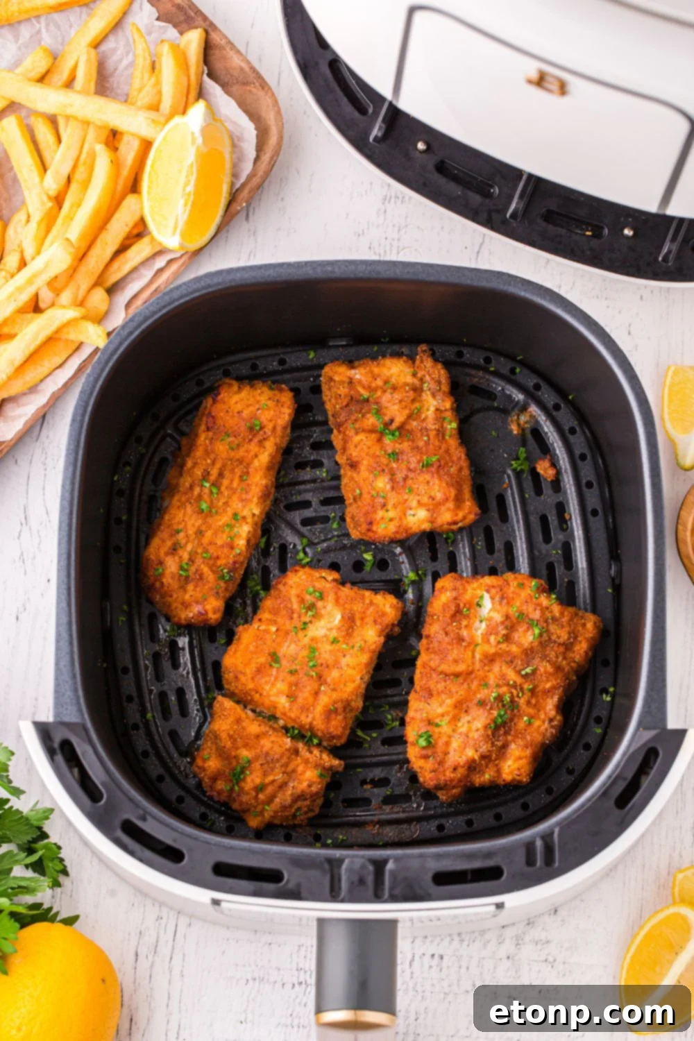 Overhead view of several breaded fish fillets neatly arranged in an air fryer basket, ready for cooking to achieve a perfect golden crisp.
