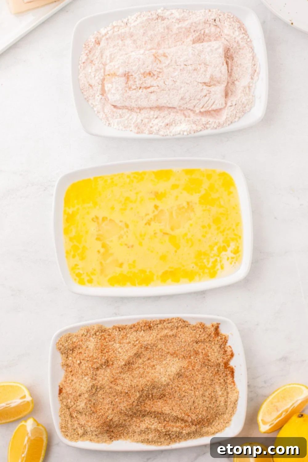 Close-up of a fish fillet being dredged in a bowl of seasoned flour, ensuring an even and thorough coating.