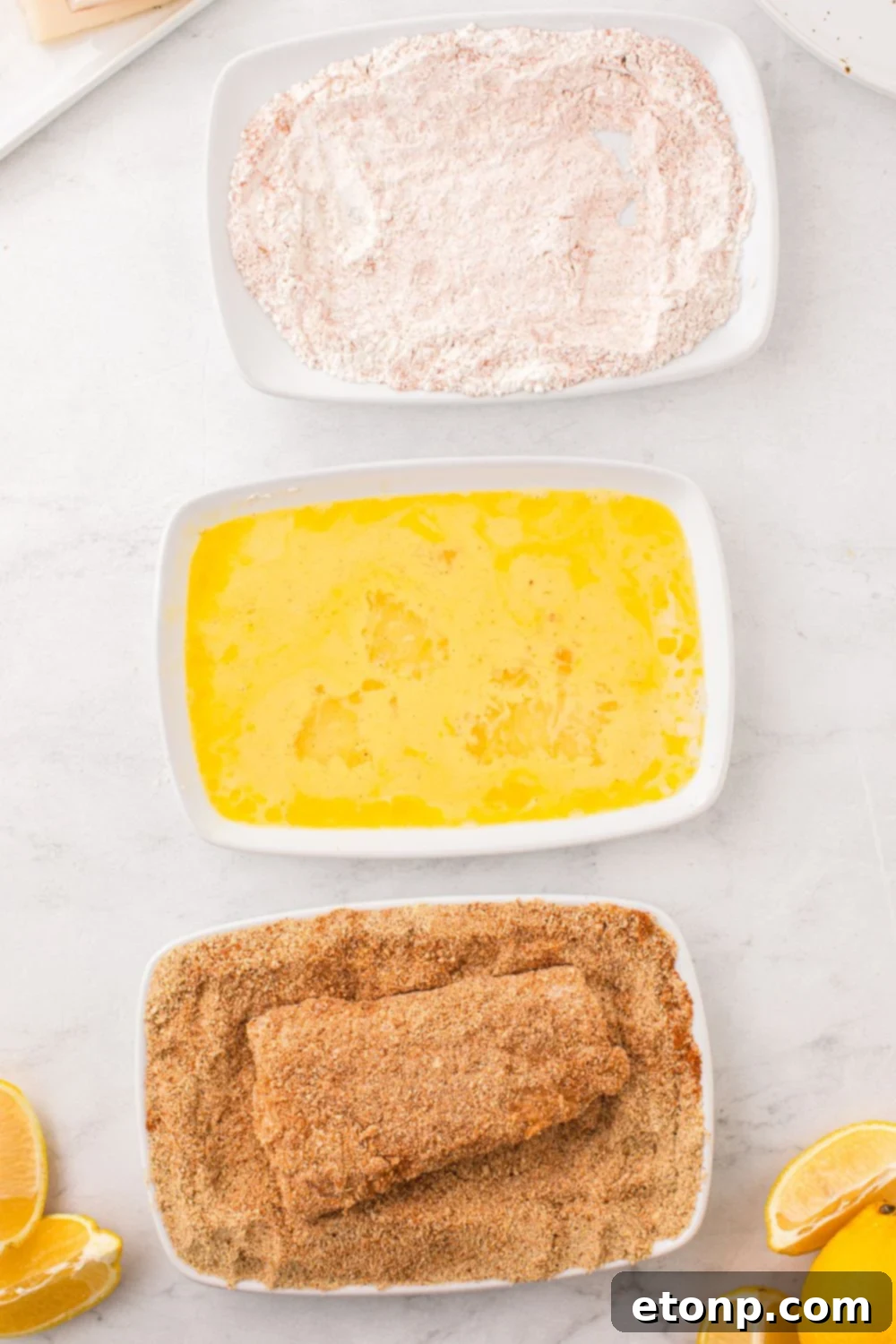 A fish fillet being pressed into a bowl of seasoned breadcrumbs, ensuring a thick, even, and crispy coating.