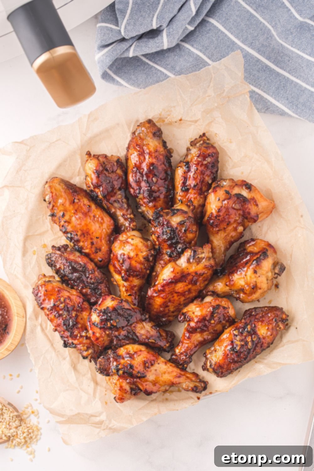 The Best Crispy Honey Garlic Air Fryer Chicken Wings 11 A plate lined with parchment paper, holding freshly air-fried honey garlic chicken wings, showing their golden color before saucing.