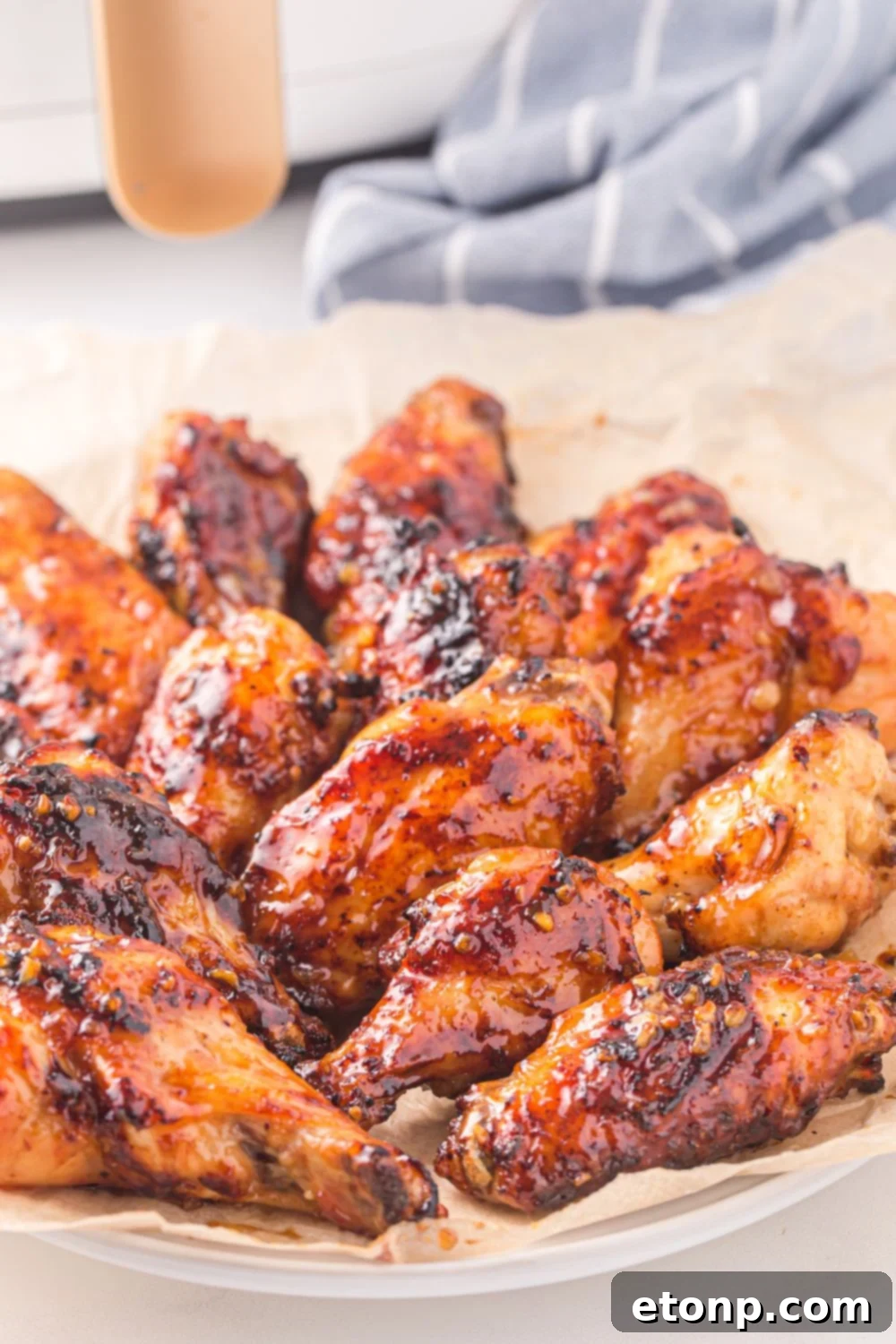 The Best Crispy Honey Garlic Air Fryer Chicken Wings 15 A plate of Air Fryer Honey Garlic Chicken Wings beautifully arranged, with a blue striped kitchen towel in the background, ready to be enjoyed.