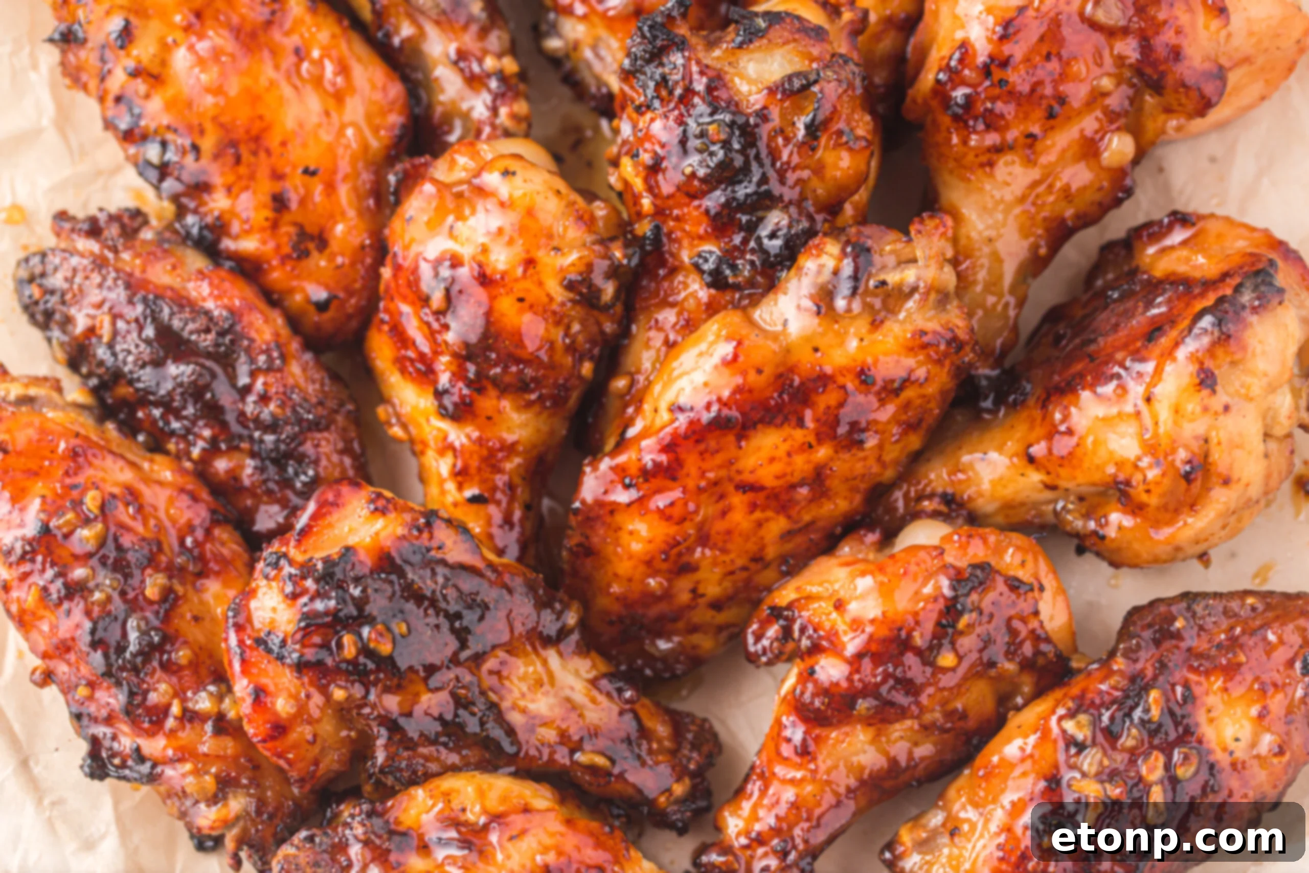 The Best Crispy Honey Garlic Air Fryer Chicken Wings 21 An overhead shot of glossy Air Fryer Honey Garlic Chicken Wings arranged on parchment paper, ready to be served.
