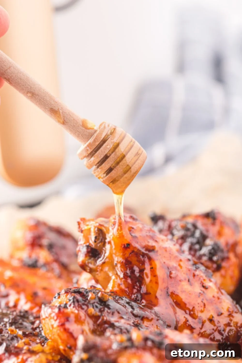 The Best Crispy Honey Garlic Air Fryer Chicken Wings 4 A plate of Air Fryer Honey Garlic Chicken Wings with a stream of honey being drizzled over them for extra sweetness and shine.
