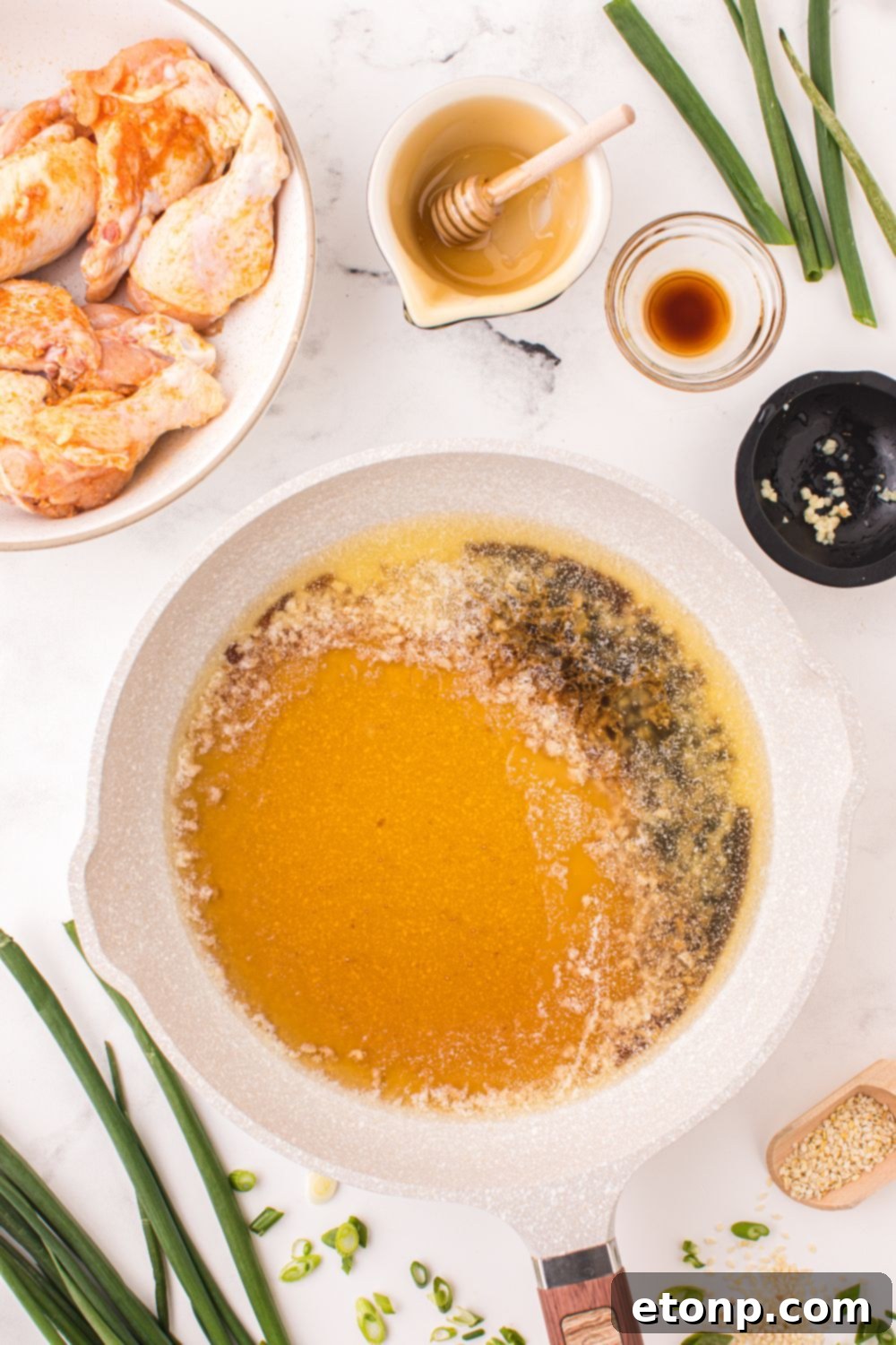 The Best Crispy Honey Garlic Air Fryer Chicken Wings 8 A small bowl of freshly made honey garlic sauce, with ingredients like honey, soy sauce, and minced garlic surrounding it, ready to be combined.