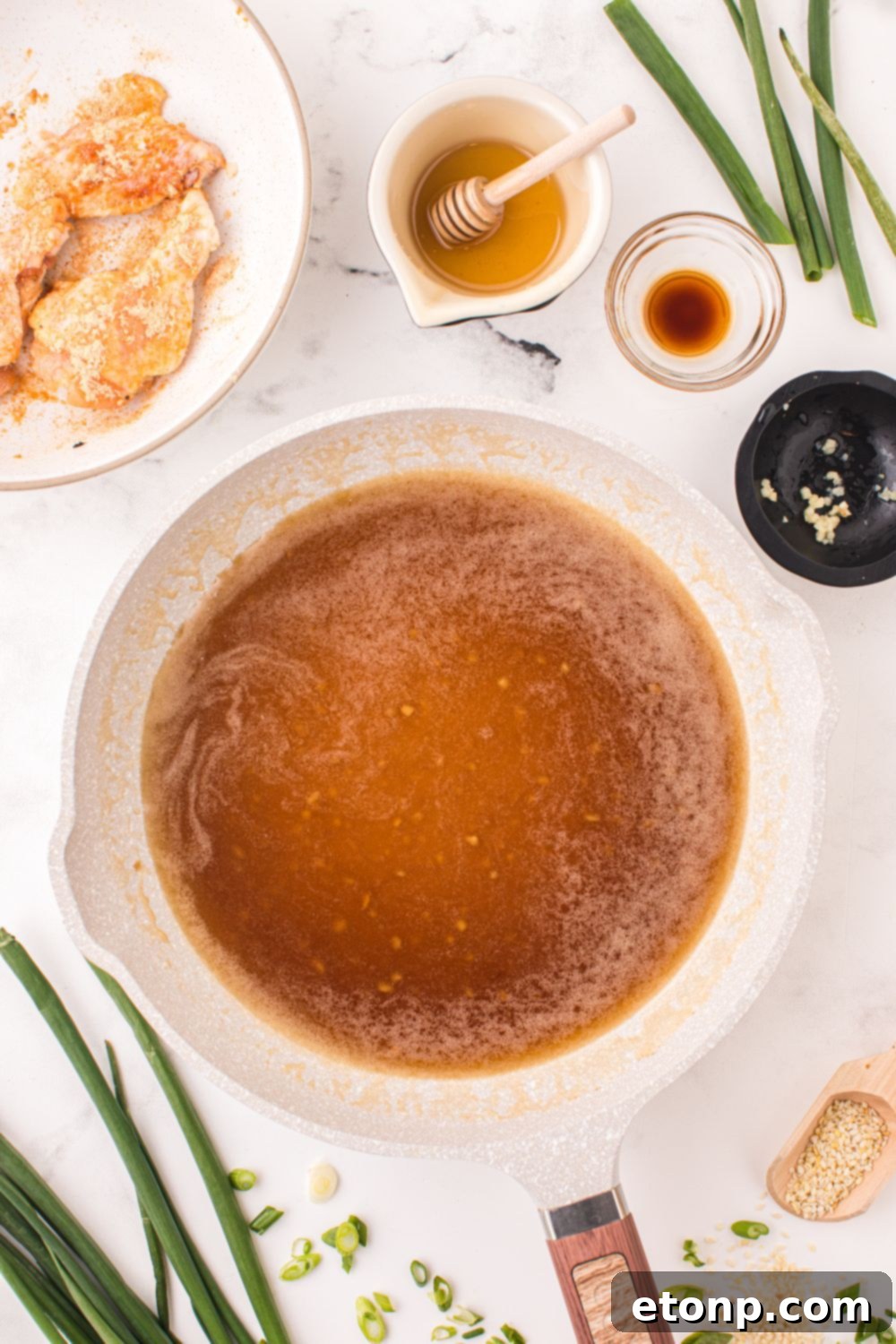 The Best Crispy Honey Garlic Air Fryer Chicken Wings 9 A saucepan on a stovetop with the honey garlic sauce simmering, surrounded by bowls of fresh ingredients.