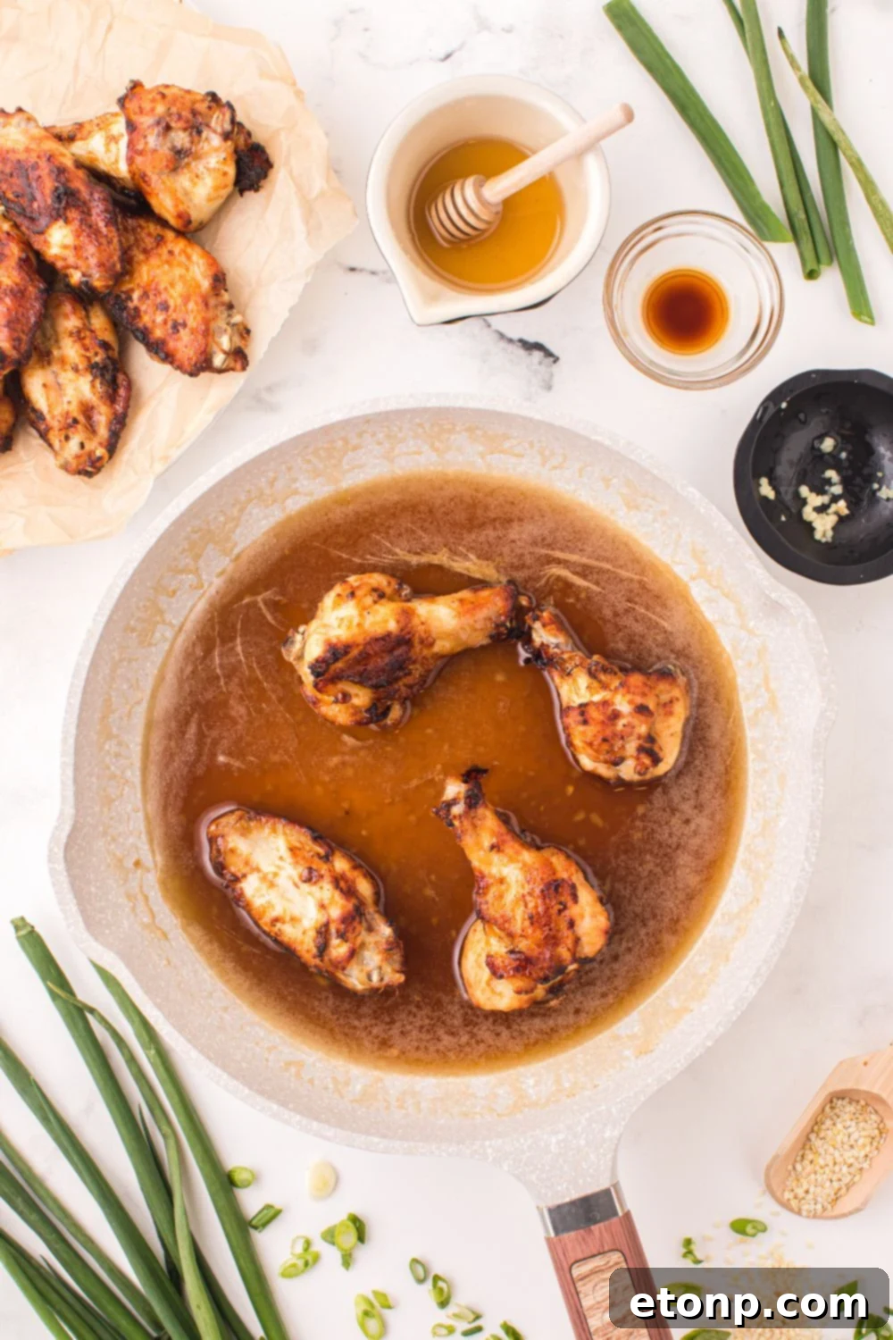 The Best Crispy Honey Garlic Air Fryer Chicken Wings 10 Crispy Air Fryer Honey Garlic Chicken Wings being tossed in a bowl of sticky, glistening honey garlic sauce, ensuring even coating.
