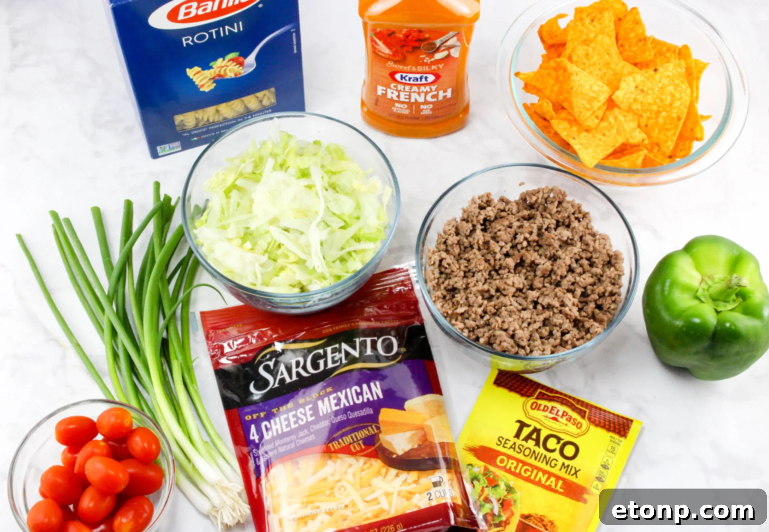 Close-up of the Doritos Taco Pasta Salad showing the texture of the rotini pasta, shredded cheese, and vibrant green bell peppers, with crushed Doritos adding a golden crunch.
