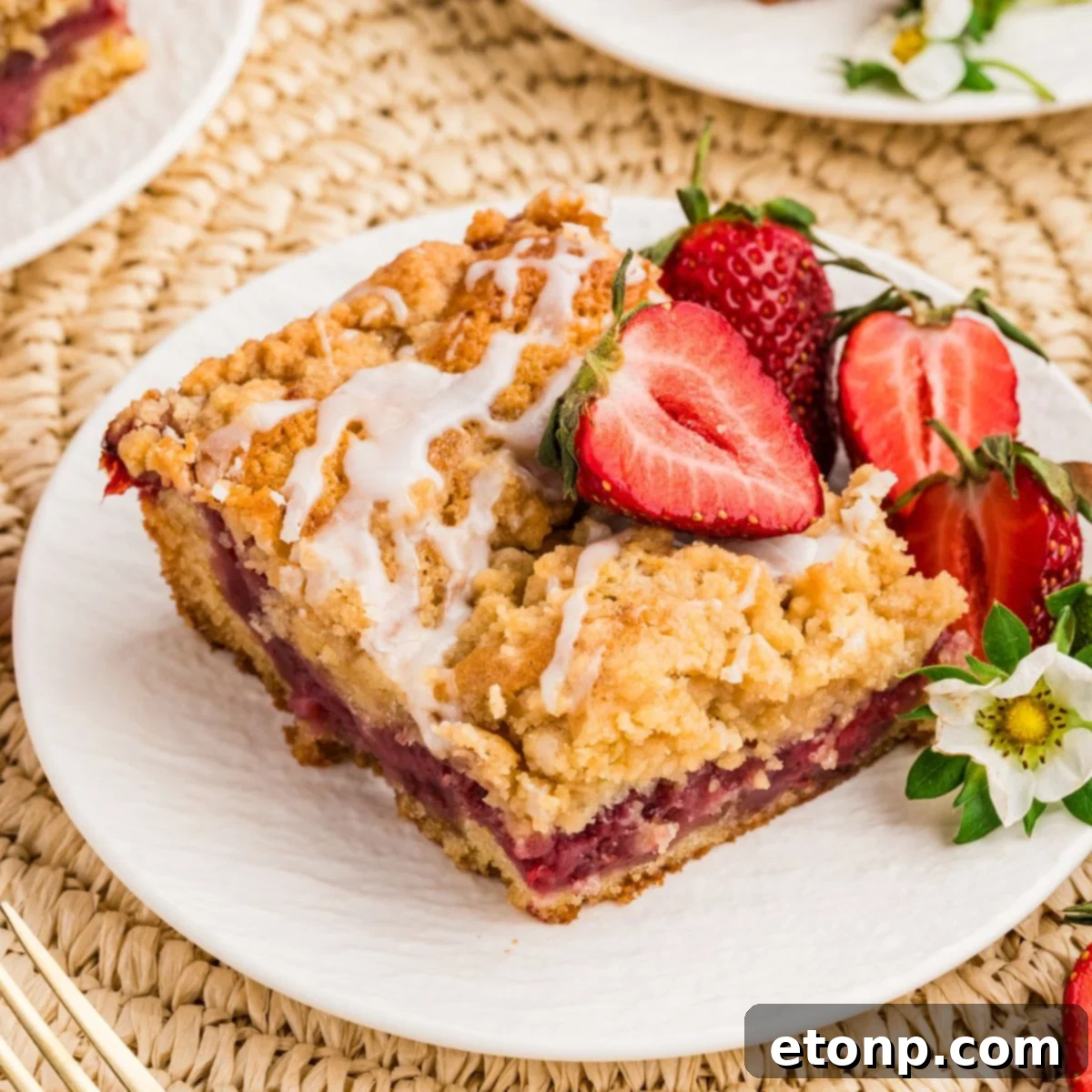 Fresh Strawberry Coffee Cake 2 A perfectly sliced Strawberry Coffee Cake on a white plate, garnished with fresh strawberries and delicate edible flowers, showcasing its tender crumb and rich strawberry swirl.
