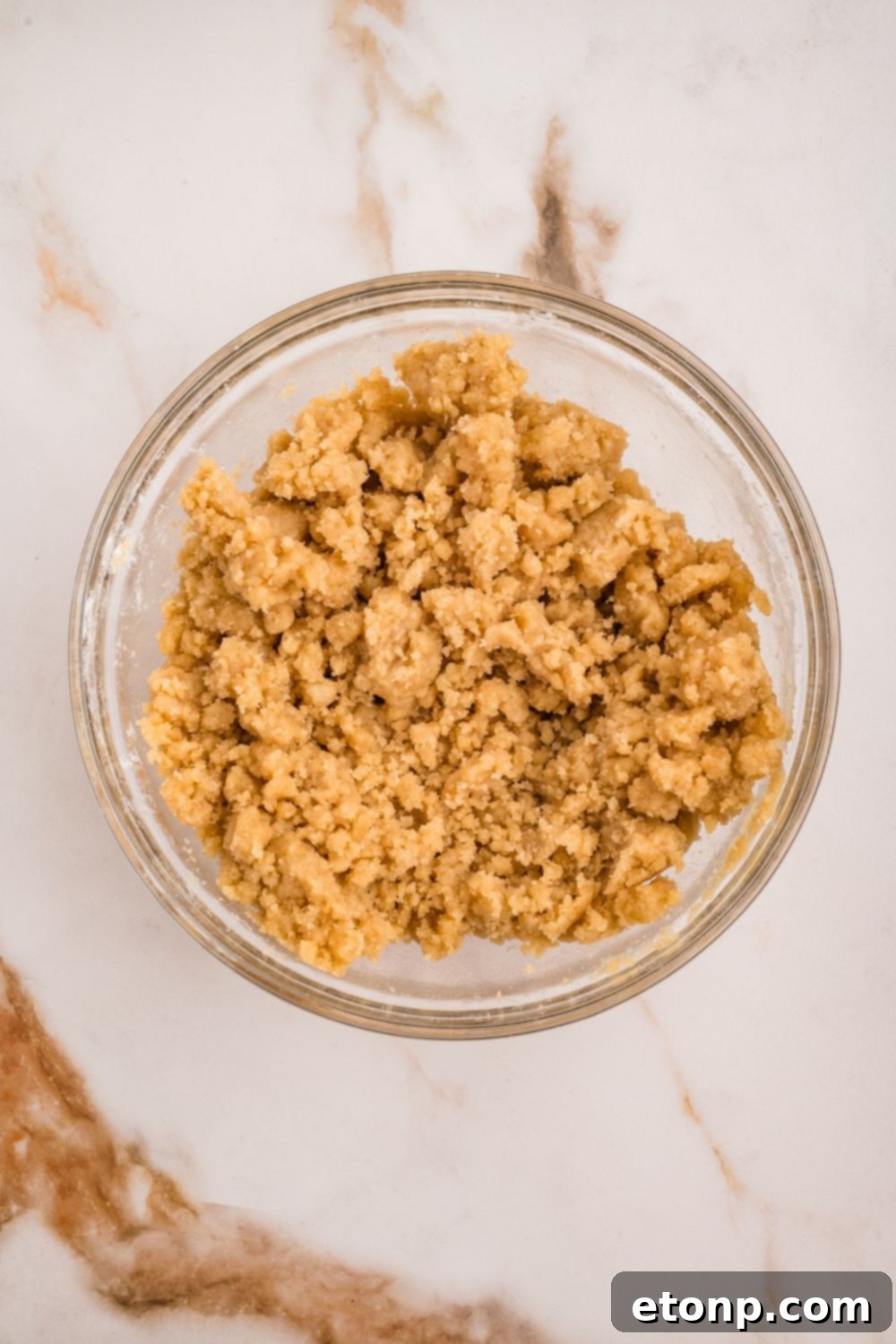 Fresh Strawberry Coffee Cake 15 A small bowl filled with the prepared crumble topping for Strawberry Coffee Cake, featuring a coarse, sandy texture.