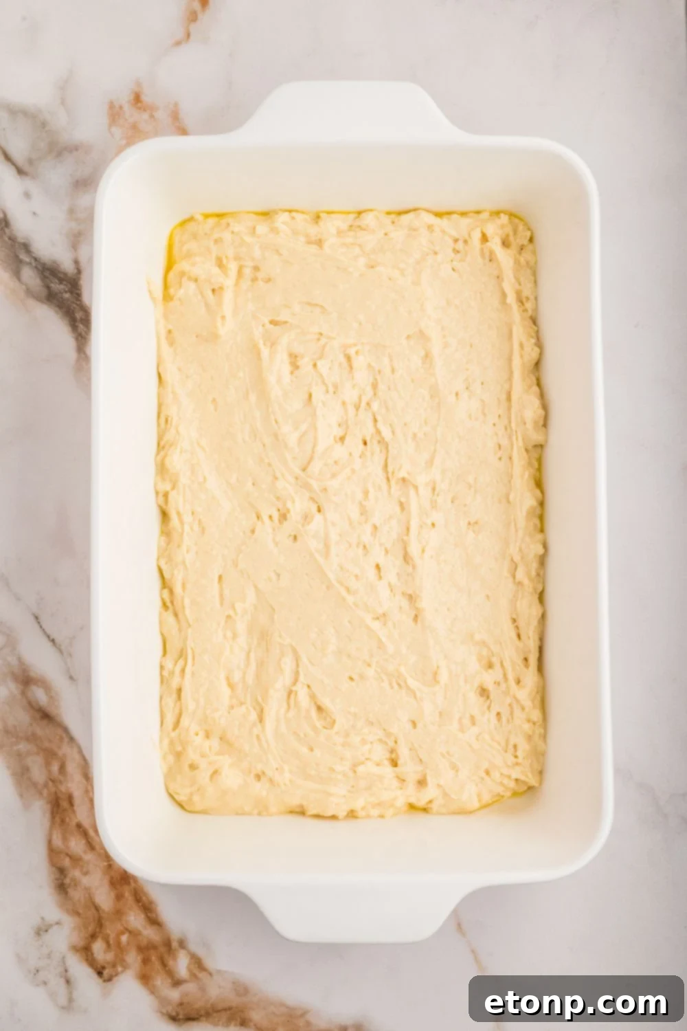 Fresh Strawberry Coffee Cake 16 Smooth, light-colored cake batter spread evenly in the bottom of a casserole dish, ready for the next layer of strawberry filling.
