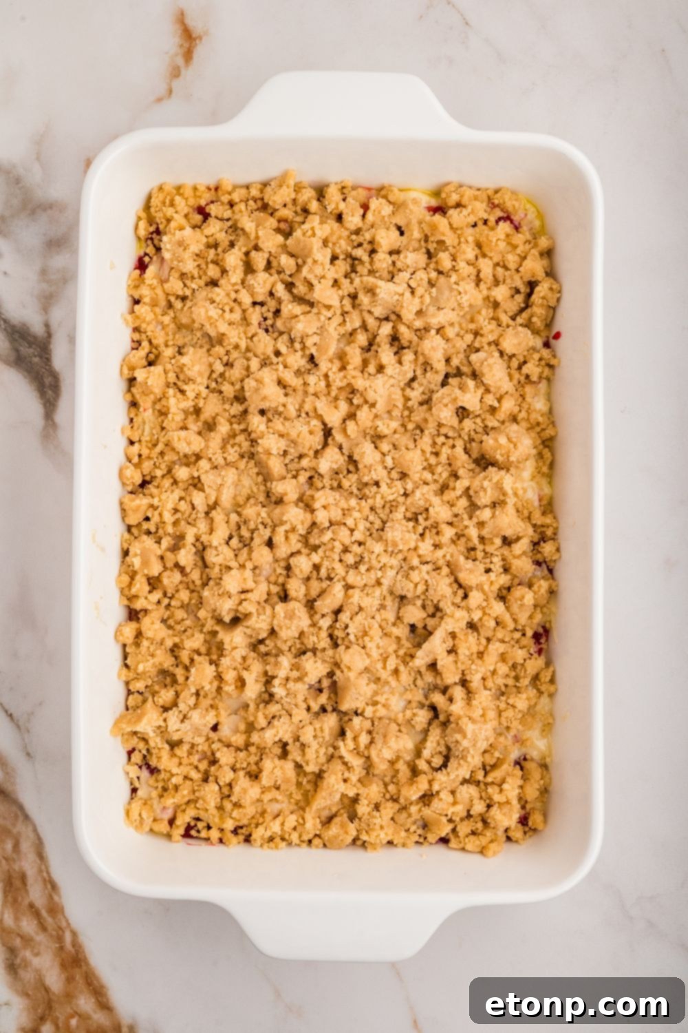 Fresh Strawberry Coffee Cake 17 An overhead view of a baking pan, showing the crumble topping generously sprinkled over the raw cake batter, creating an enticing texture.