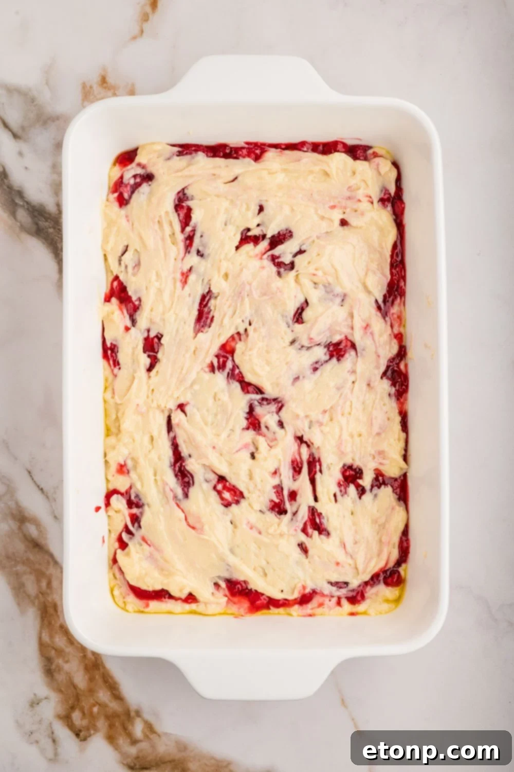 Fresh Strawberry Coffee Cake 19 Unbaked Strawberry Coffee Cake batter, with swirls of fruit filling visible, spread in a casserole dish, ready for the oven.