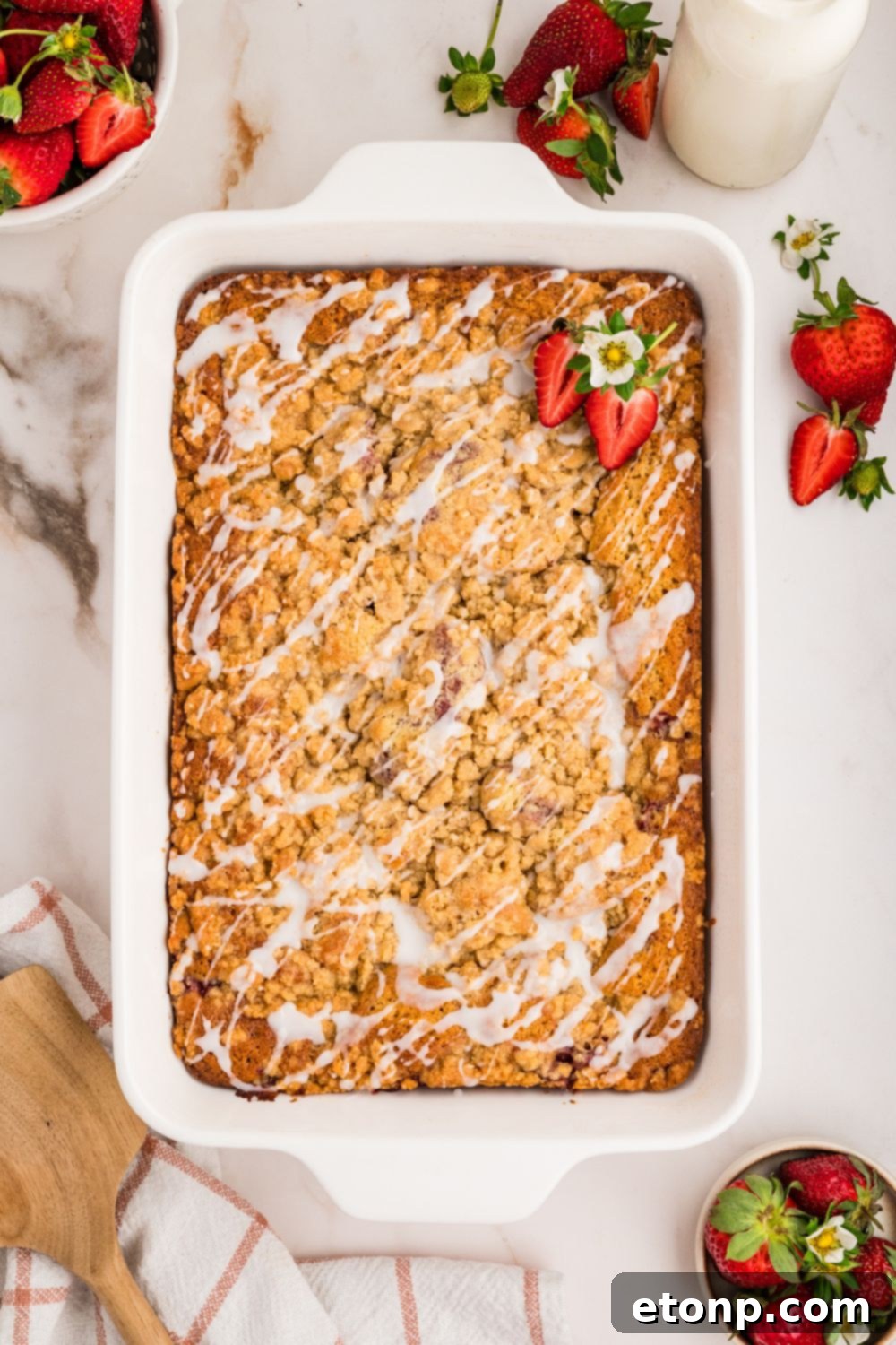 Fresh Strawberry Coffee Cake 20 An overhead shot of an unbaked Strawberry Coffee Cake in a pan on a table, showcasing the layers of batter, strawberry filling, and crumble topping.