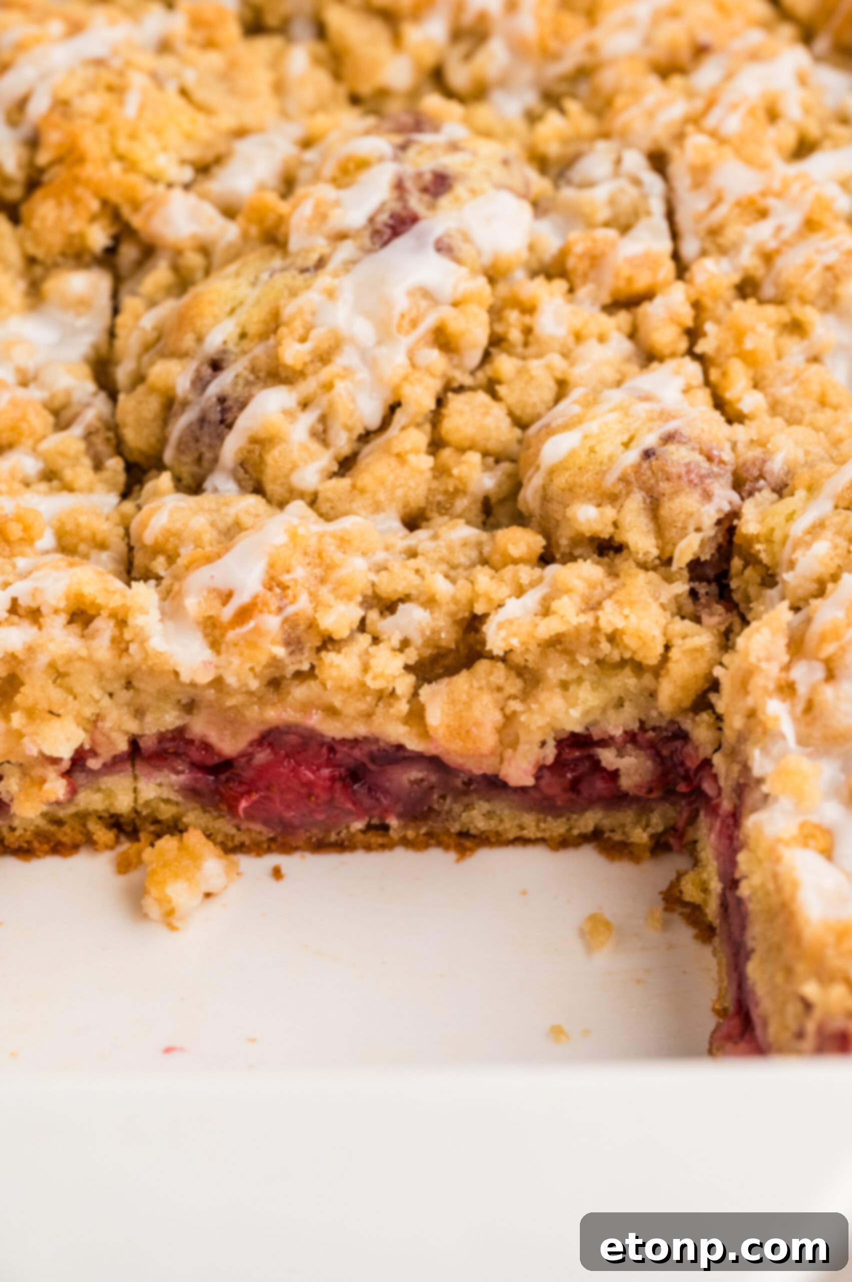 Fresh Strawberry Coffee Cake 3 Close-up view of a Strawberry Coffee Cake still in its baking pan, highlighting the golden brown, textured crumble topping and inviting strawberry peeks.