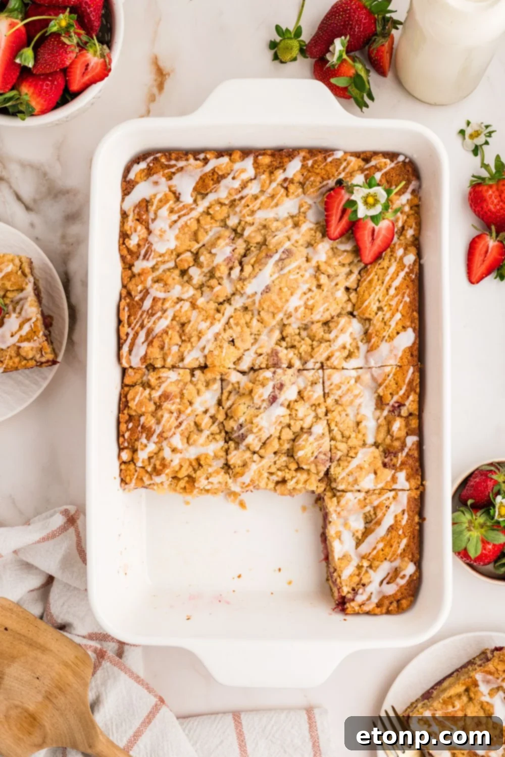 Fresh Strawberry Coffee Cake 21 A Strawberry Coffee Cake in a baking pan with several slices already cut out, revealing the soft interior and rich strawberry swirls.