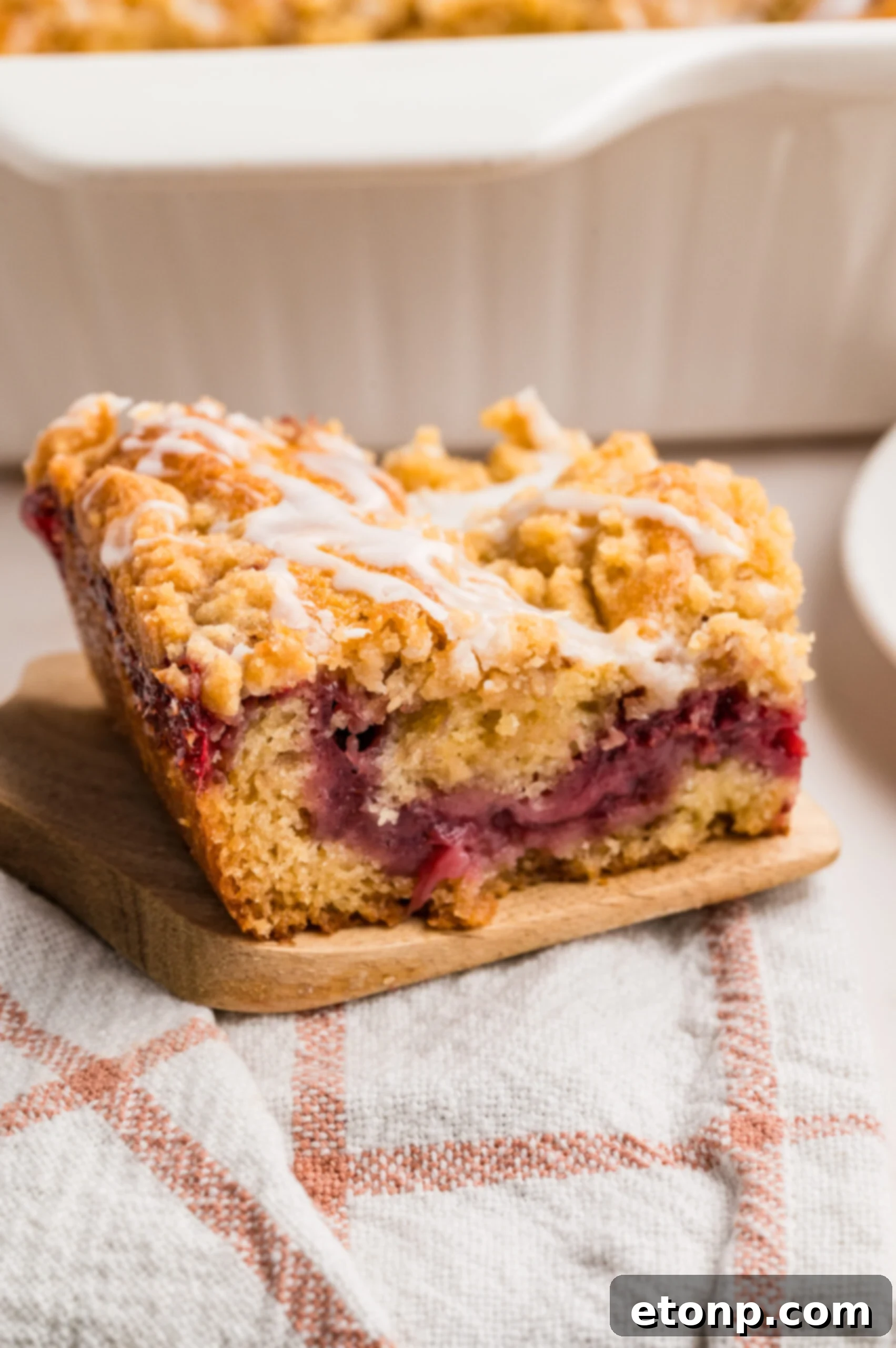 Fresh Strawberry Coffee Cake 6 A slice of Strawberry Coffee Cake resting on a rustic wooden spatula, placed on a simple table, ready to be enjoyed.