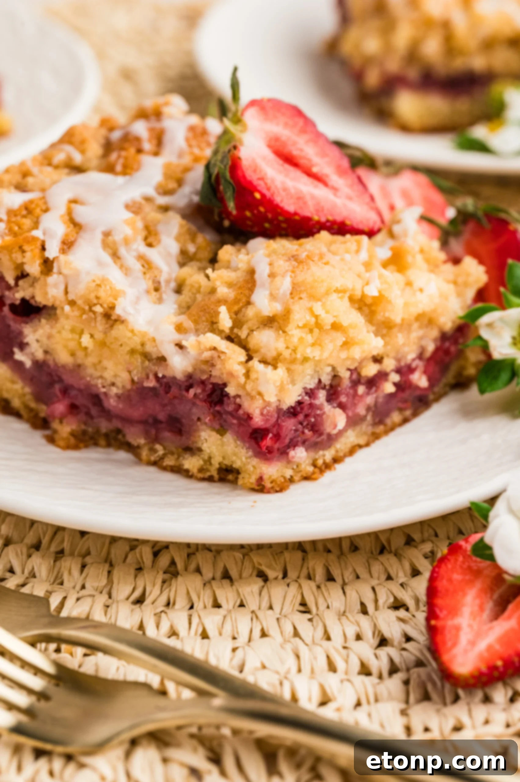 Fresh Strawberry Coffee Cake 7 A single slice of Strawberry Coffee Cake beautifully presented on a white plate, adorned with fresh strawberry slices, emphasizing its inviting texture.