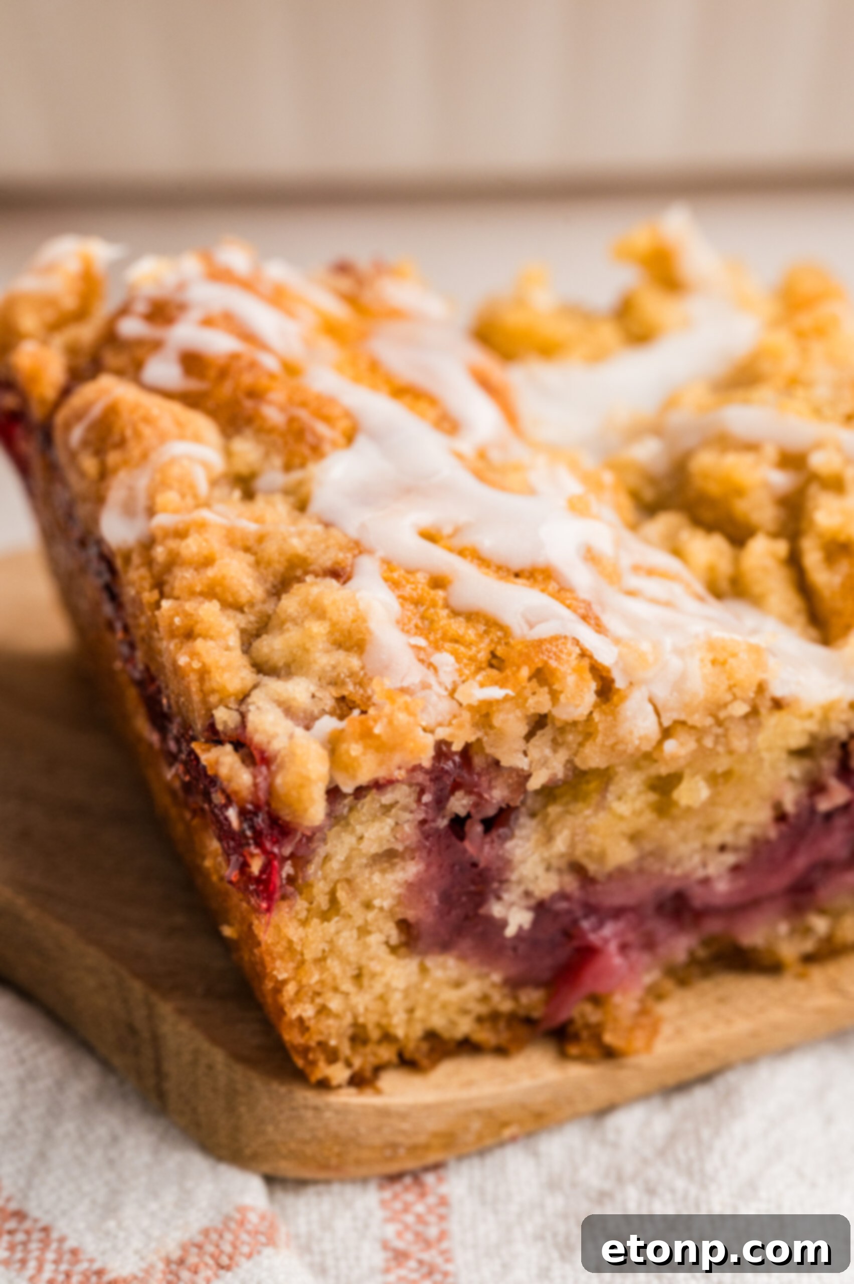 Fresh Strawberry Coffee Cake 8 A rustic cutting board holds a generous slice of Strawberry Coffee Cake, highlighting the rich crumb and vibrant fruit filling.