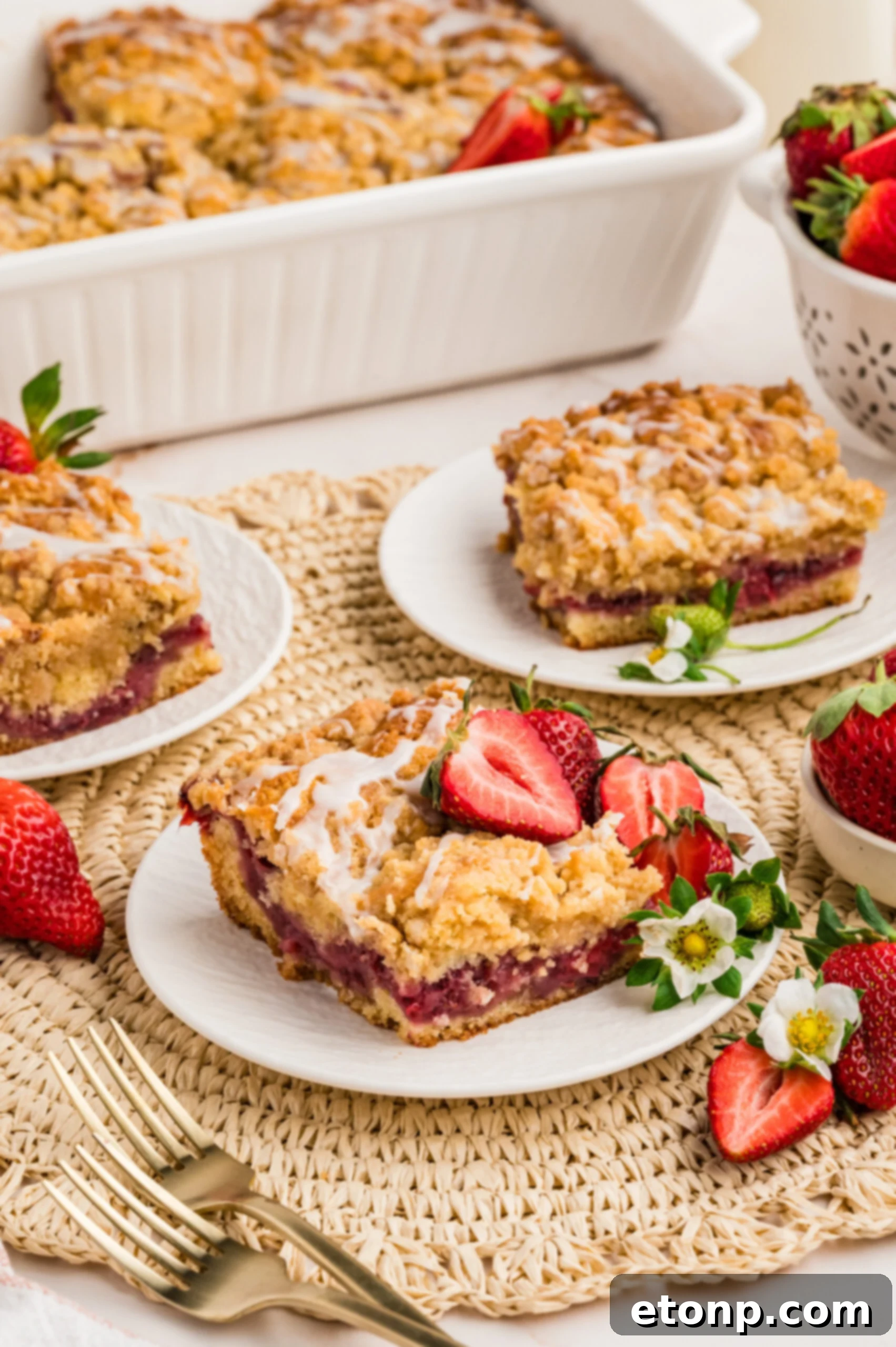 Fresh Strawberry Coffee Cake 9 A white plate featuring a slice of Strawberry Coffee Cake, delicately garnished with fresh strawberry slices and small white flowers, showcasing its elegance.