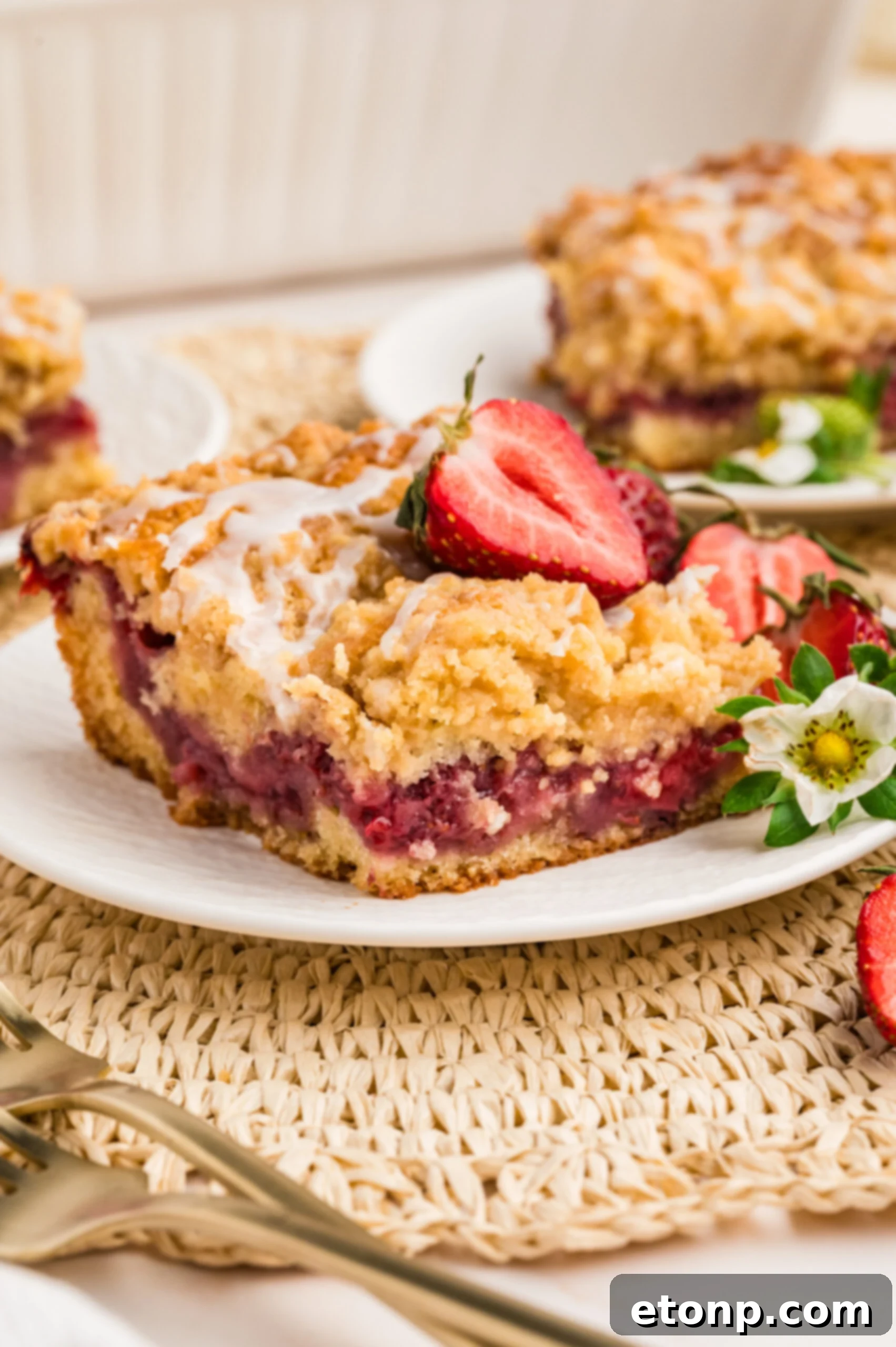 Fresh Strawberry Coffee Cake 10 A close-up shot of a Strawberry Coffee Cake slice on a white plate, revealing the intricate layers of cake, strawberry filling, and crumb topping.