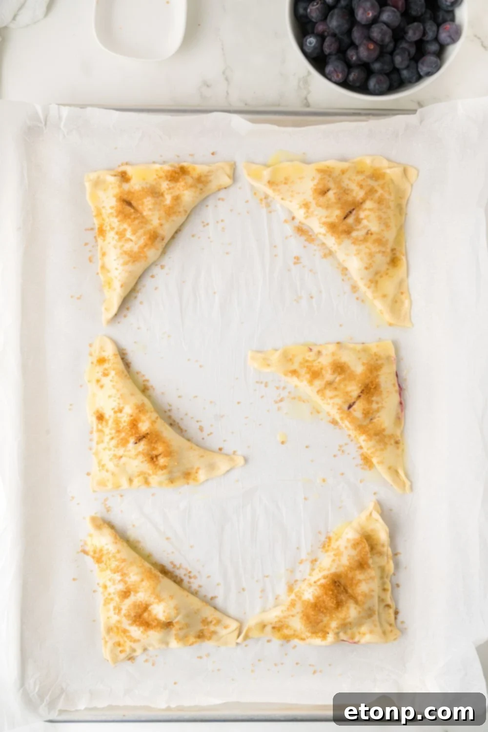 Blueberry Turnovers on tray brushed with butter 