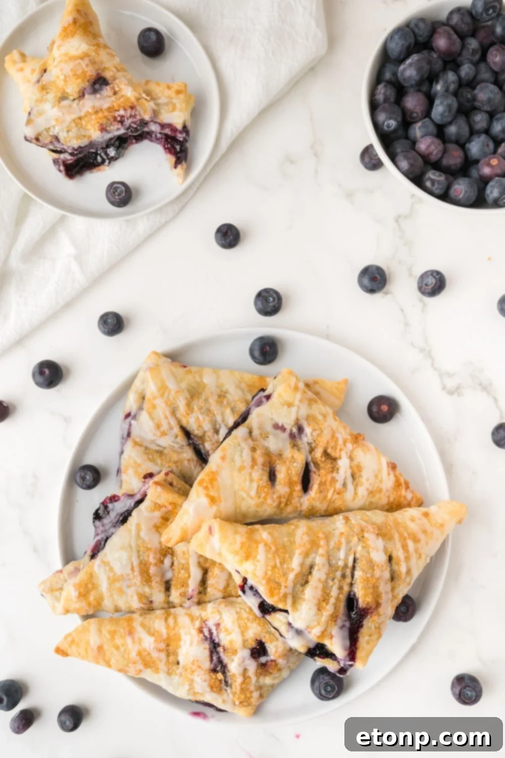 overhead look of a plate full of Blueberry Turnovers with some berries to the side 