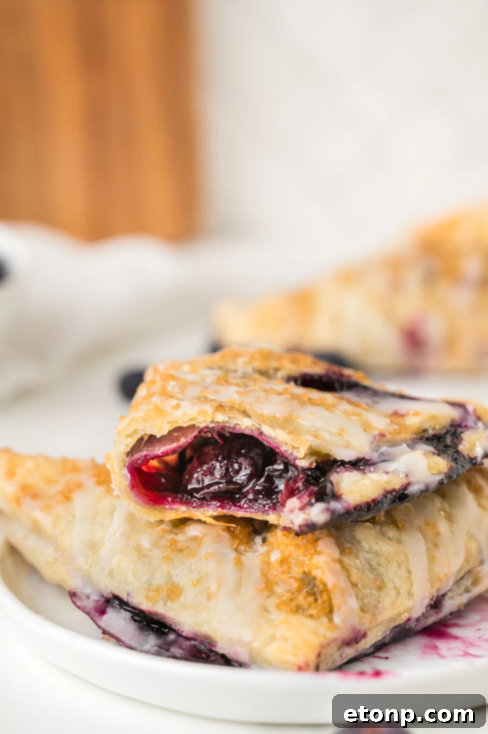 Blueberry Turnovers on plate with a bite missing drizzled with icing 