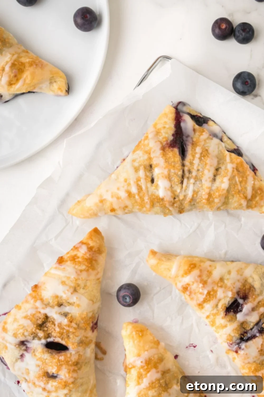 Blueberry Turnovers spread out on sheet pan covered with parchment paper 