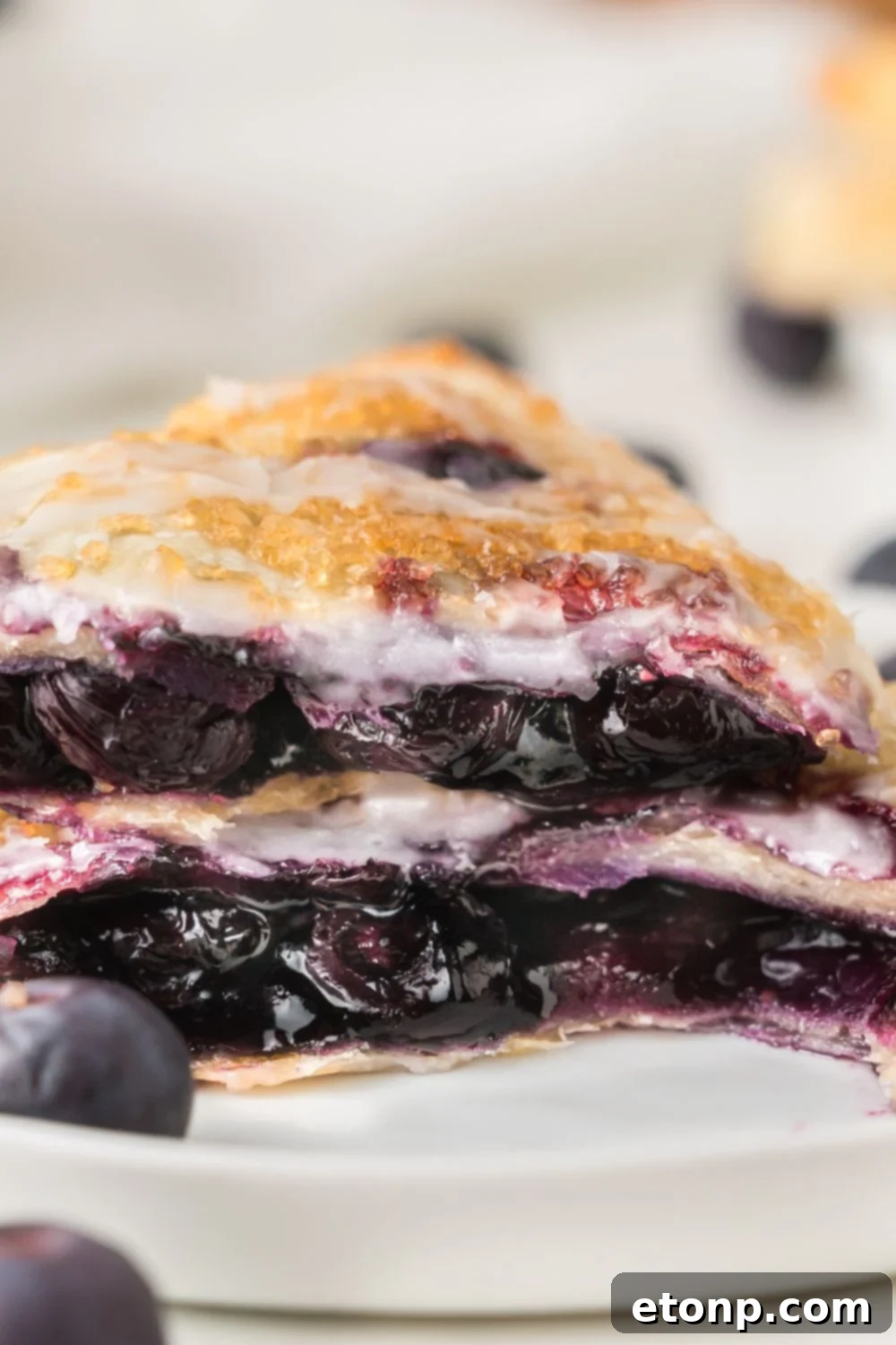 Blueberry Turnover cut in half and stacked on top of each other to showcase the blueberry filling inside the pastry 