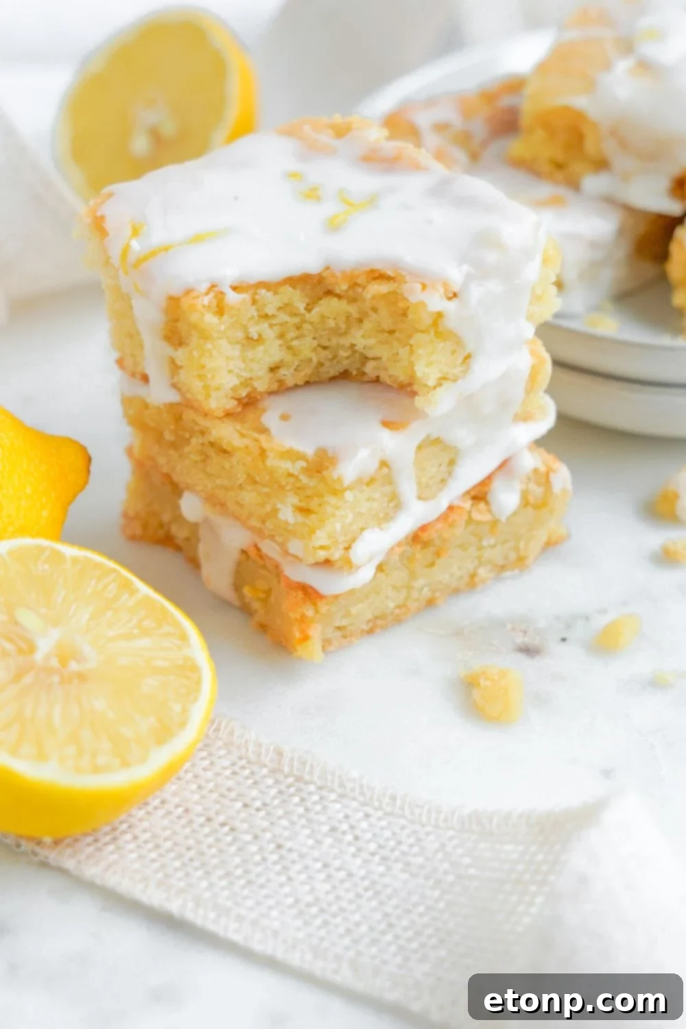 Lemon Sugar Cookie Bars stacked on top of one another with top bar having a bite taken out of it 