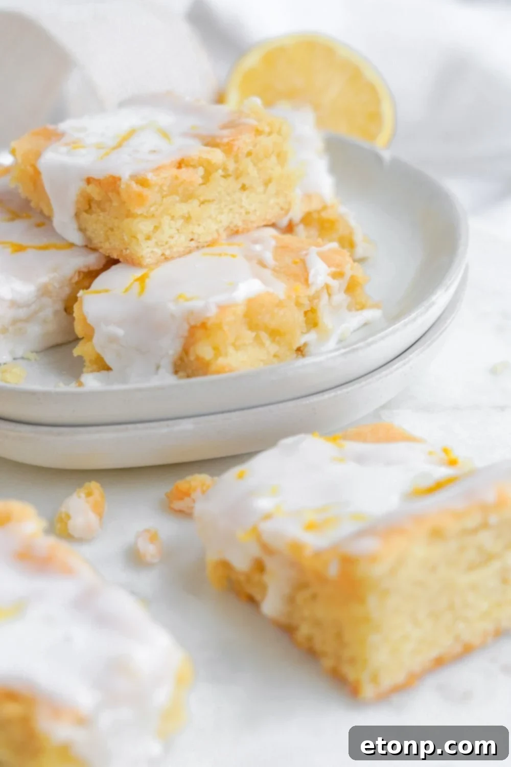 plate with lemon cookie bars and some of the bars are placed on table as well