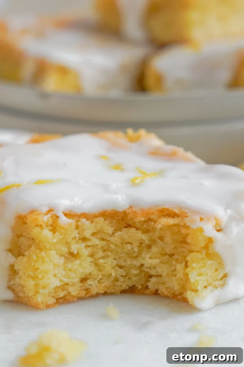 Lemon Sugar Cookie Bar sitting on table with a bite taken out of the bars to show close up of center of bar