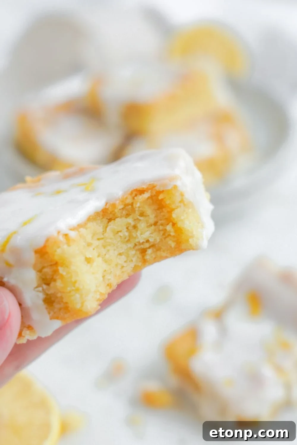Lemon Sugar Cookie Bar being held in hand with a bite taken out of it 