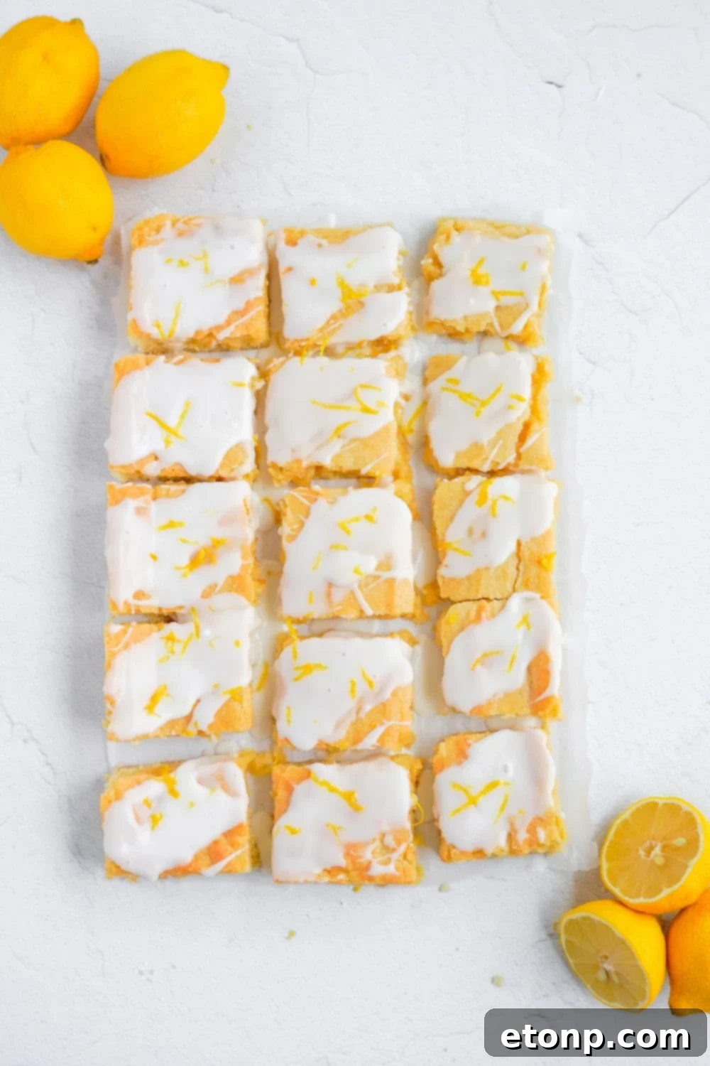 cut Lemon Sugar Cookie Bars on table with lemons on edge of bars 
