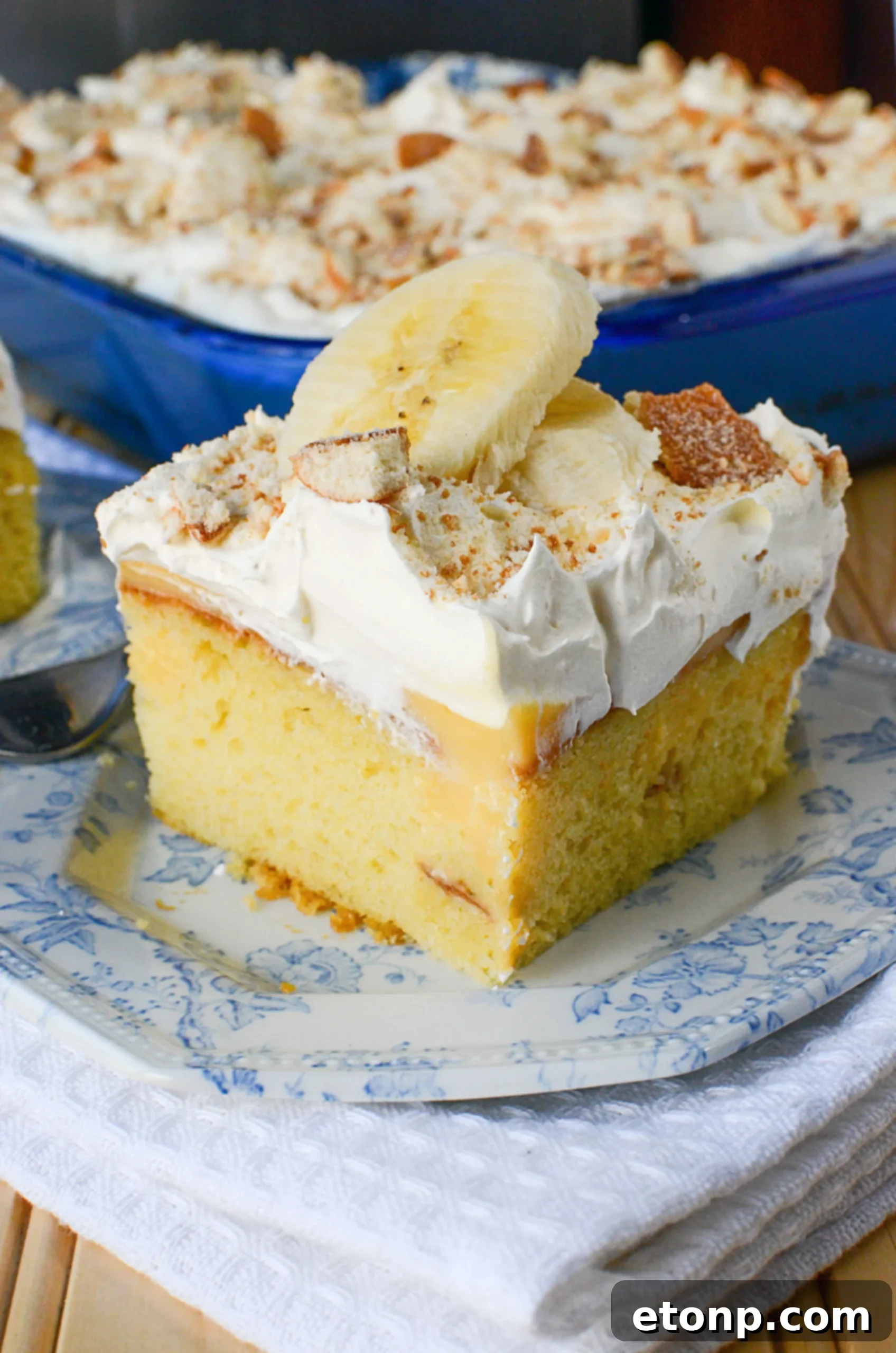 Close-up of fresh banana slices layered over the vanilla pudding in the poke cake
