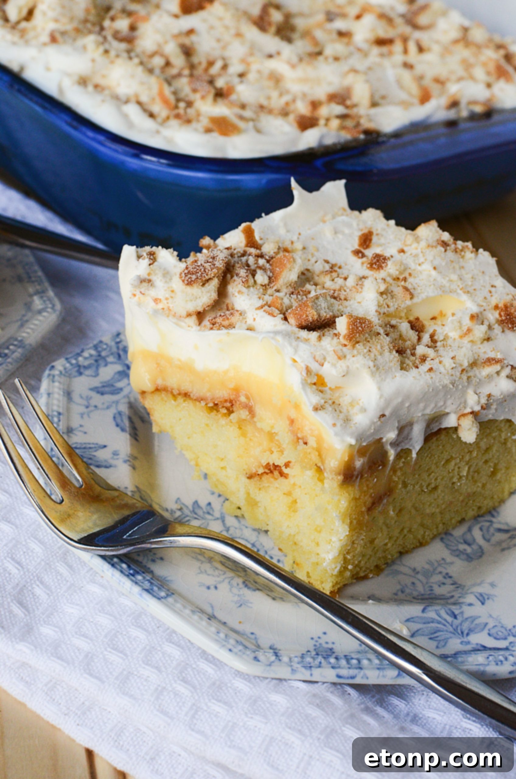 A square serving of Banana Lush Poke Cake on a plate, ready to be eaten