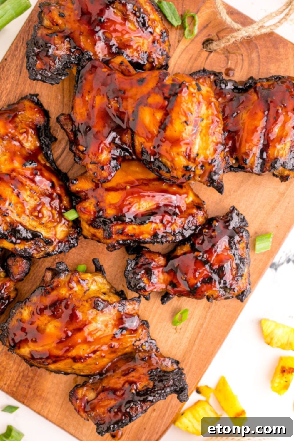 Grilled Huli Huli Chicken proudly displayed on a wooden board, garnished with vibrant fresh herbs