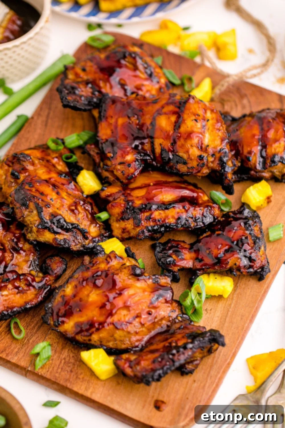 A festive table setting featuring a large platter of Huli Huli Chicken, garnished with fresh green onions for a pop of color