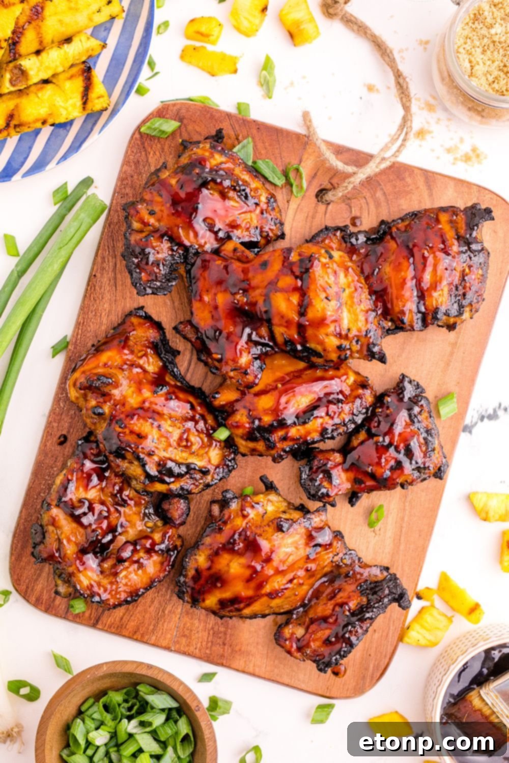 An inviting overhead view of a table laden with Huli Huli Chicken, garnished with green onions and surrounded by fresh pineapple, ready for a tropical feast