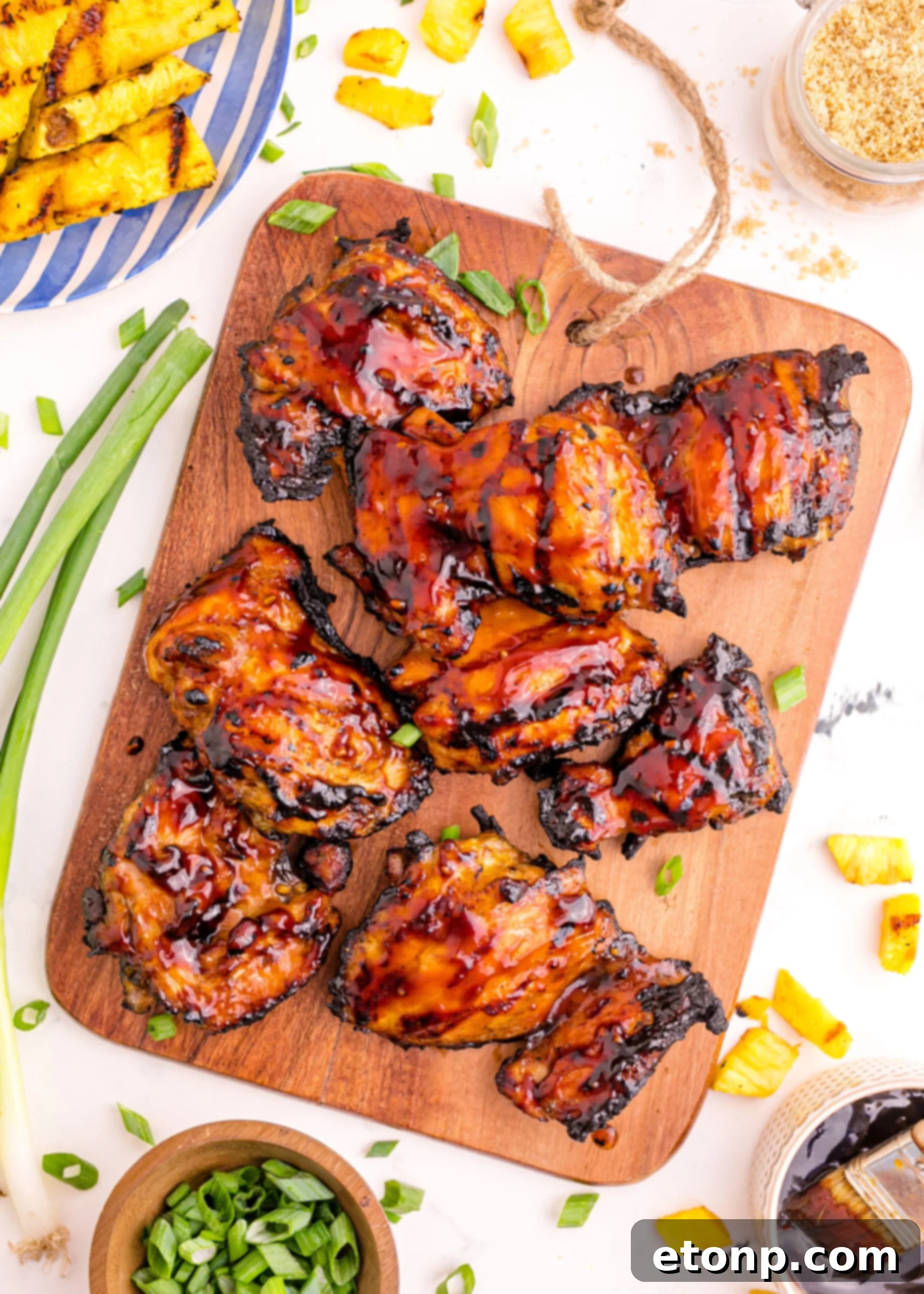 A close-up shot of perfectly grilled Huli Huli Chicken resting on a wooden cutting board, highlighting its appealing glaze